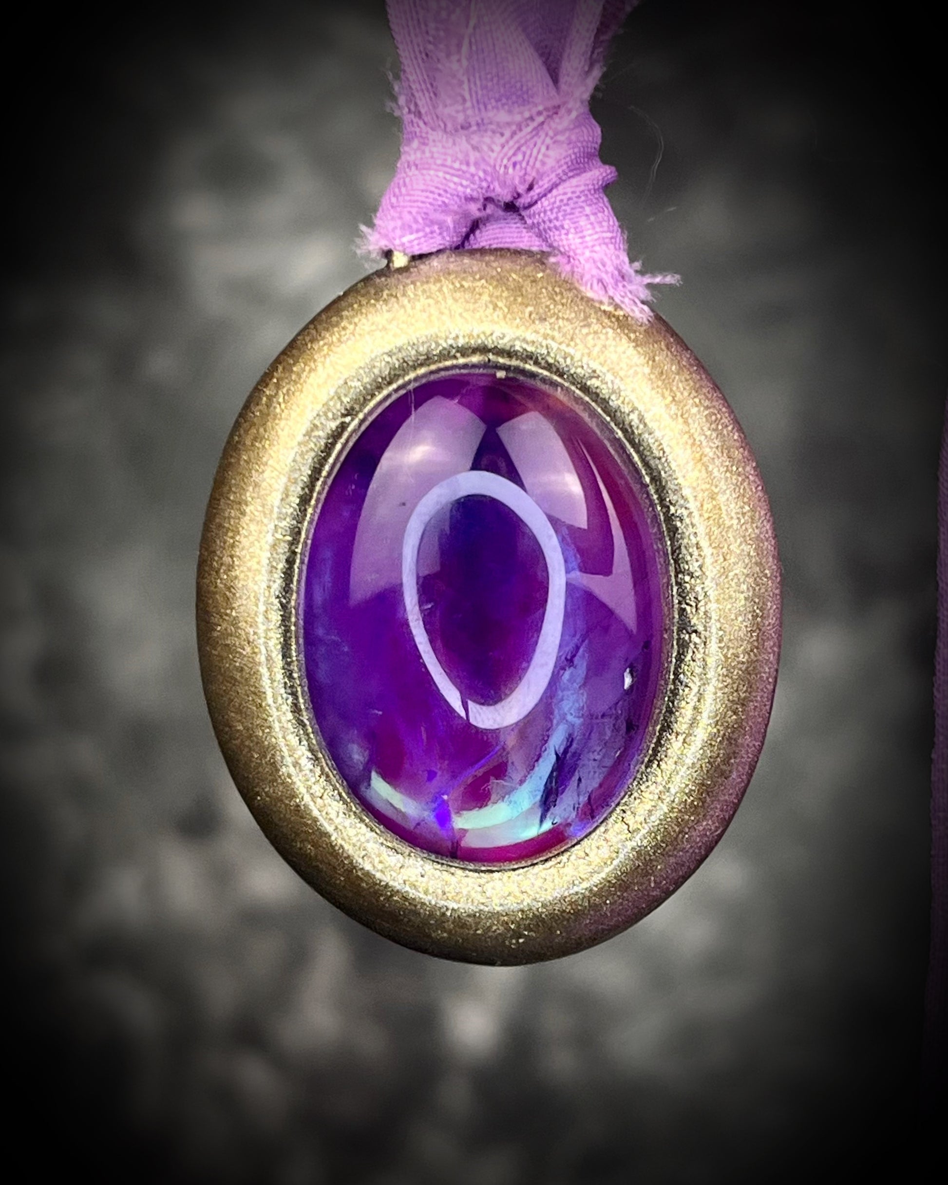 Mystical amethyst talisman with soft nebula glow, sculpted gold finish, and lilac recycled silk ties by Become Spellbound.