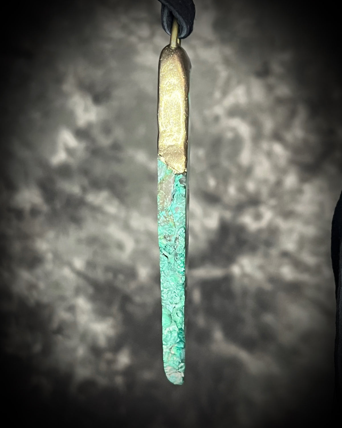 Natural malachite slab with distinctive green banding in a sculptural gold-finish talisman setting on black leather, handmade by Become Spellbound in Baltimore, Maryland.