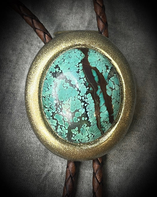 Natural turquoise bolo tie with distinctive double brown stripe resembling claw marks, brown leather, gold finish, and gold spike tips.