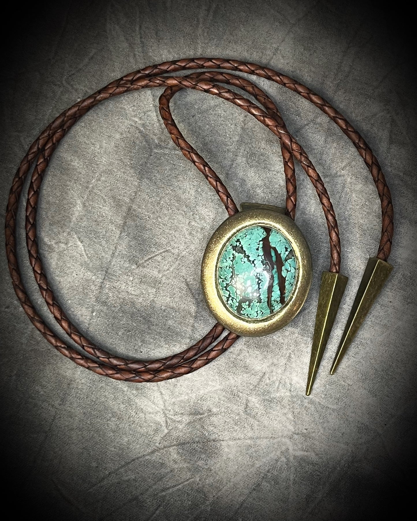 Natural turquoise bolo tie with distinctive double brown stripe resembling claw marks, brown leather, gold finish, and gold spike tips.