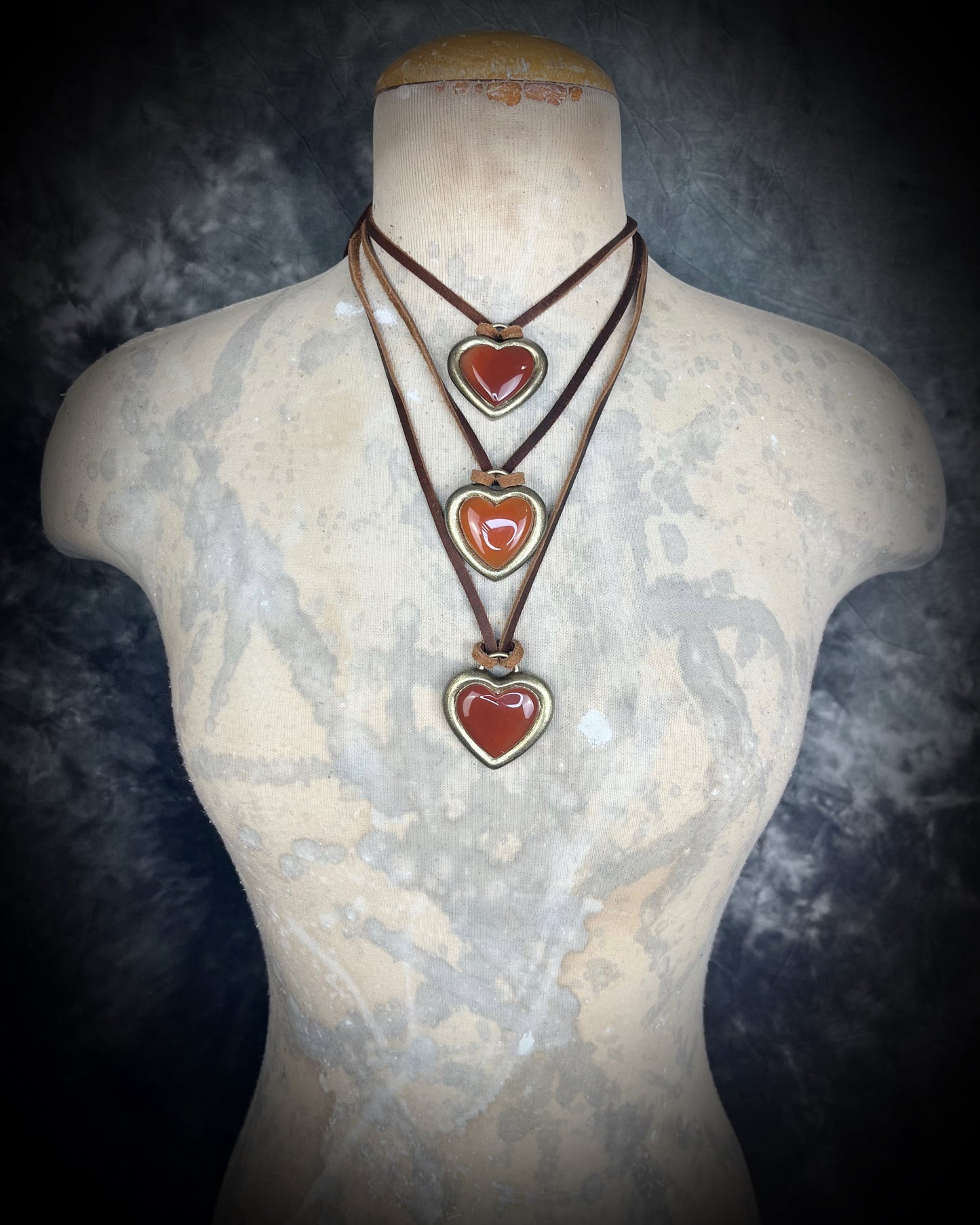 Necklace with carnelian crystal heart-shaped pendants on a mannequin bust against a dark background