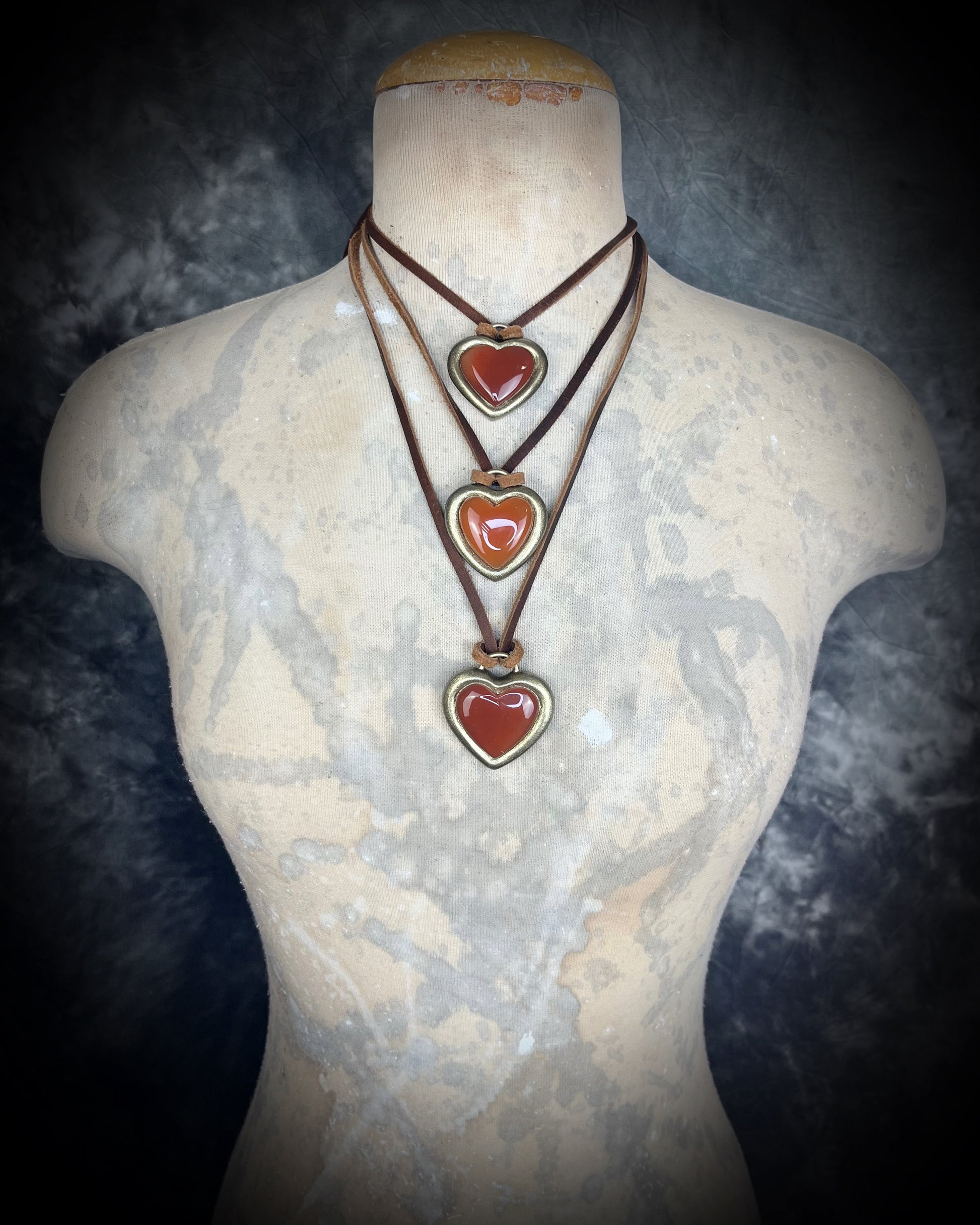 Necklace with carnelian crystal heart-shaped pendants on a mannequin bust against a dark background