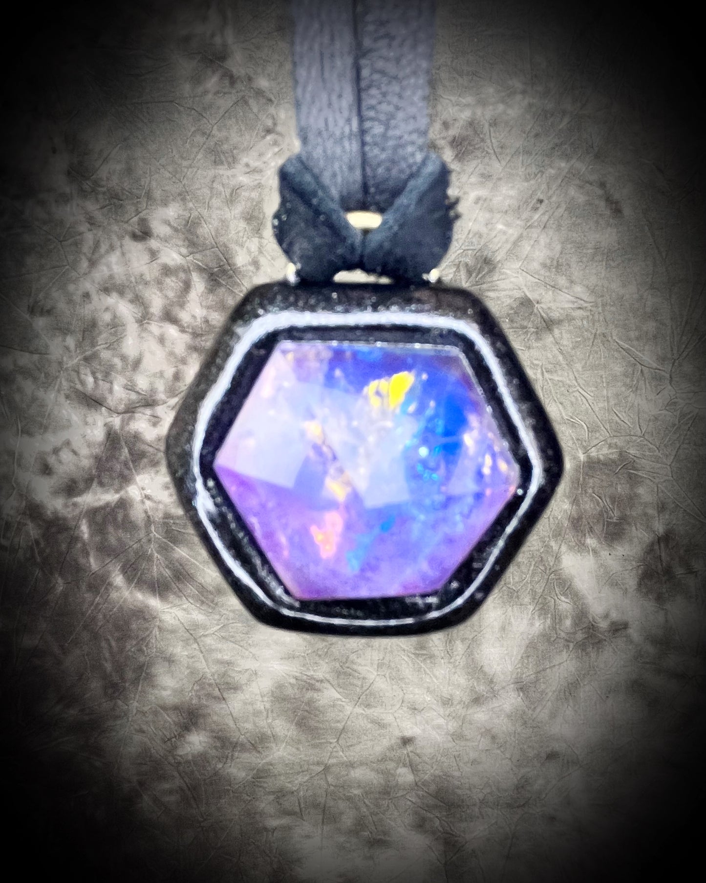 Opalescent amethyst hexagon pendant framed in black on black leather cord — handmade mystical crystal talisman necklace.