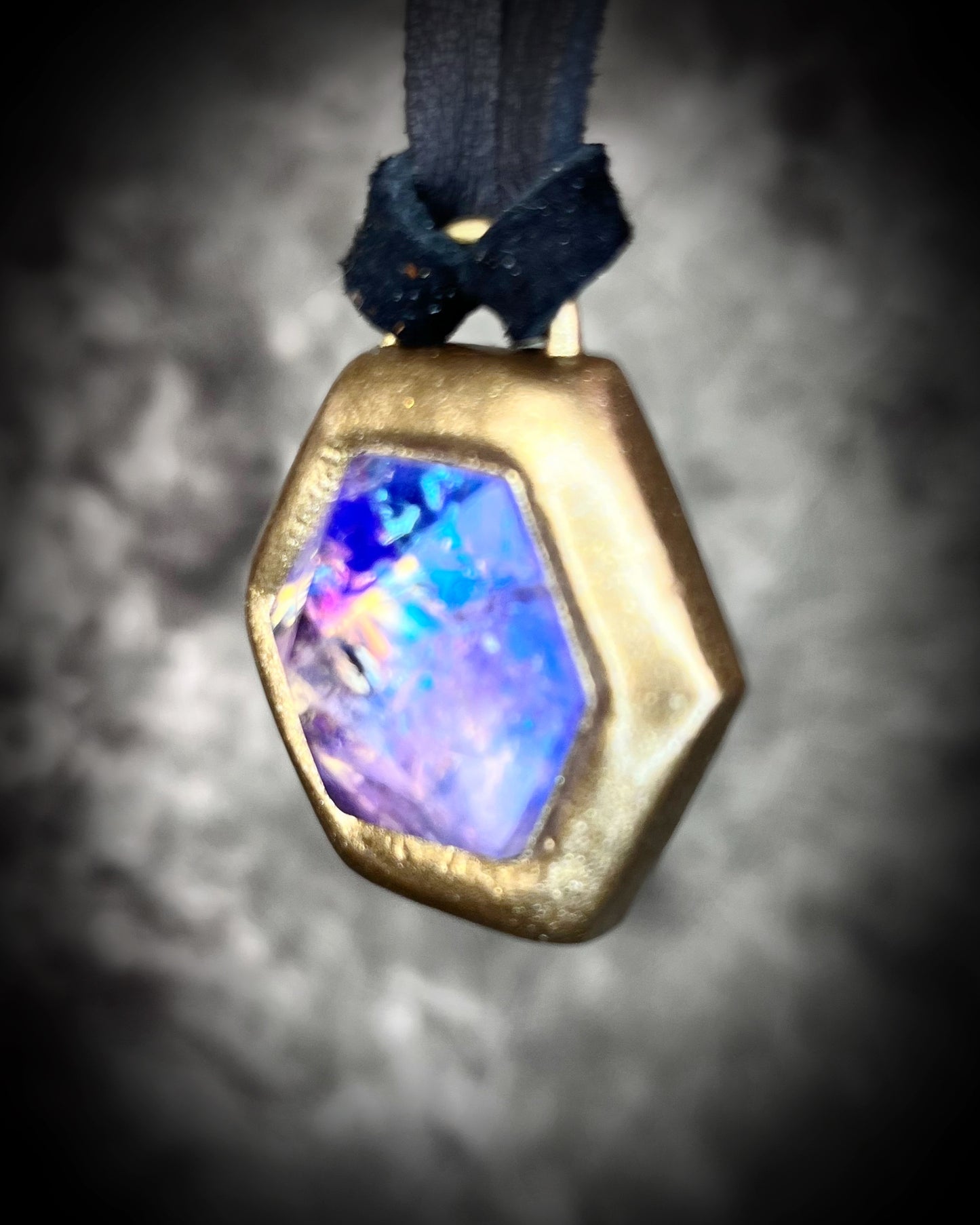 Opalescent amethyst hexagon pendant framed in gold on black leather cord — handmade mystical crystal talisman necklace.