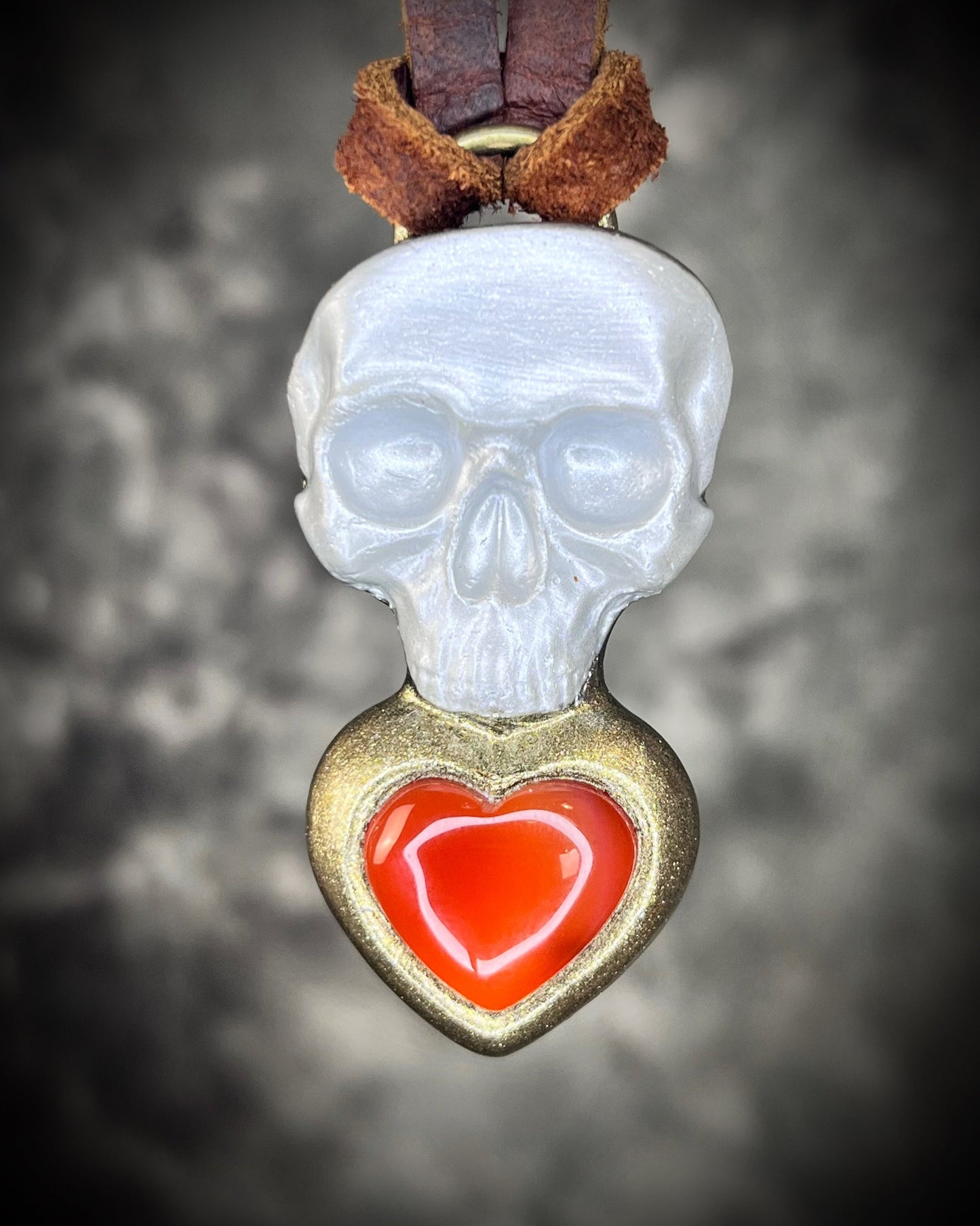 Pearl white skull pendant with gold-framed Carnelian heart on brown leather — mystical talisman necklace.