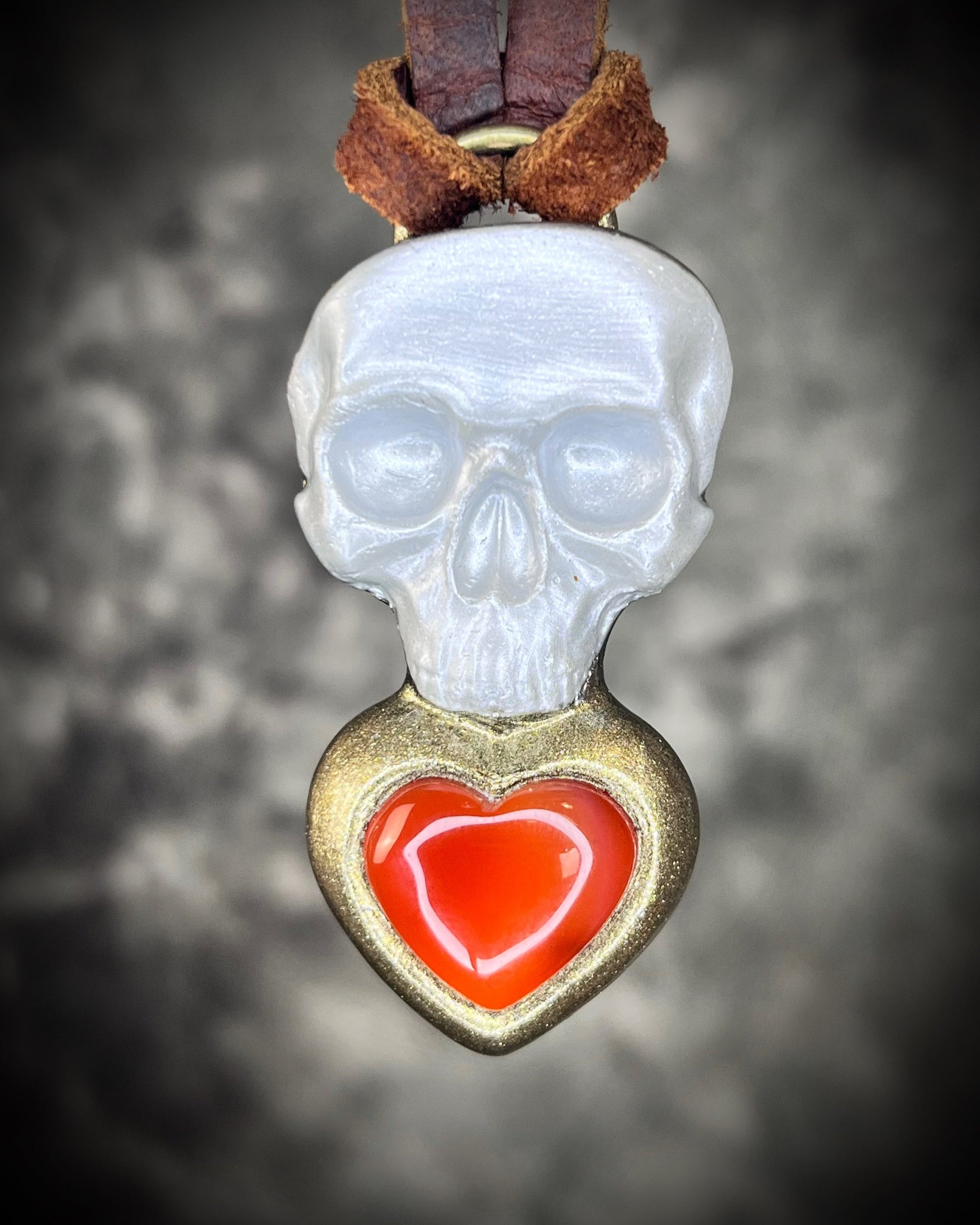 Pearl white skull pendant with gold-framed Carnelian heart on brown leather — mystical talisman necklace.