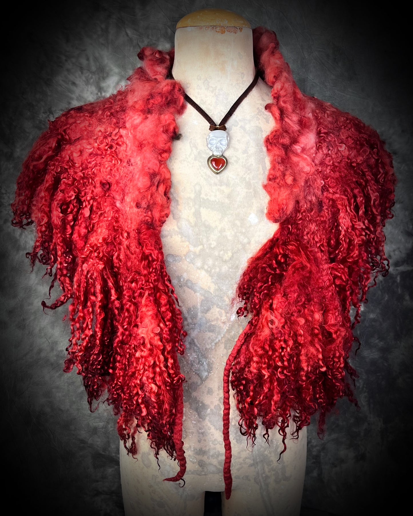 Pearl white skull pendant with gold-framed Carnelian heart on brown leather — mystical talisman necklace worn on a bust with a red curly felted wool collar.