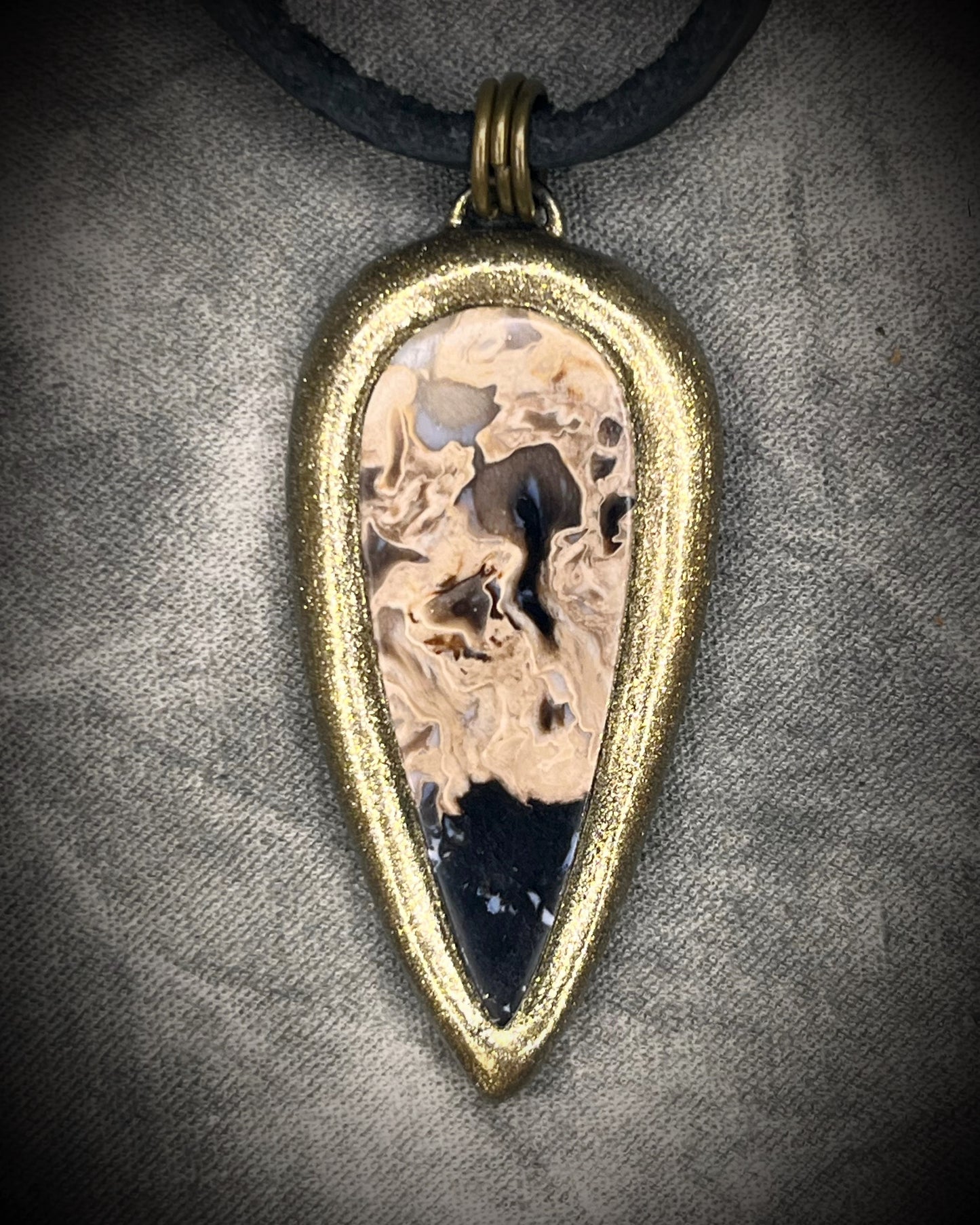 Petrified palm root necklace, teardrop shaped and set in a gold finish. Fossilized wood pendant hung from black leather for a protective and grounding vibe. 