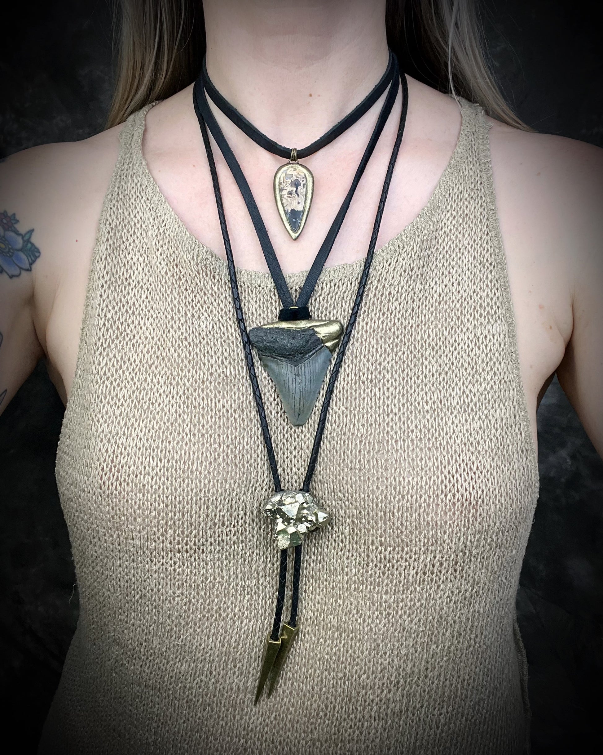 Petrified palm root necklace, teardrop shaped and set in a gold finish. Fossilized wood pendant hung from black leather for a protective and grounding vibe. 
