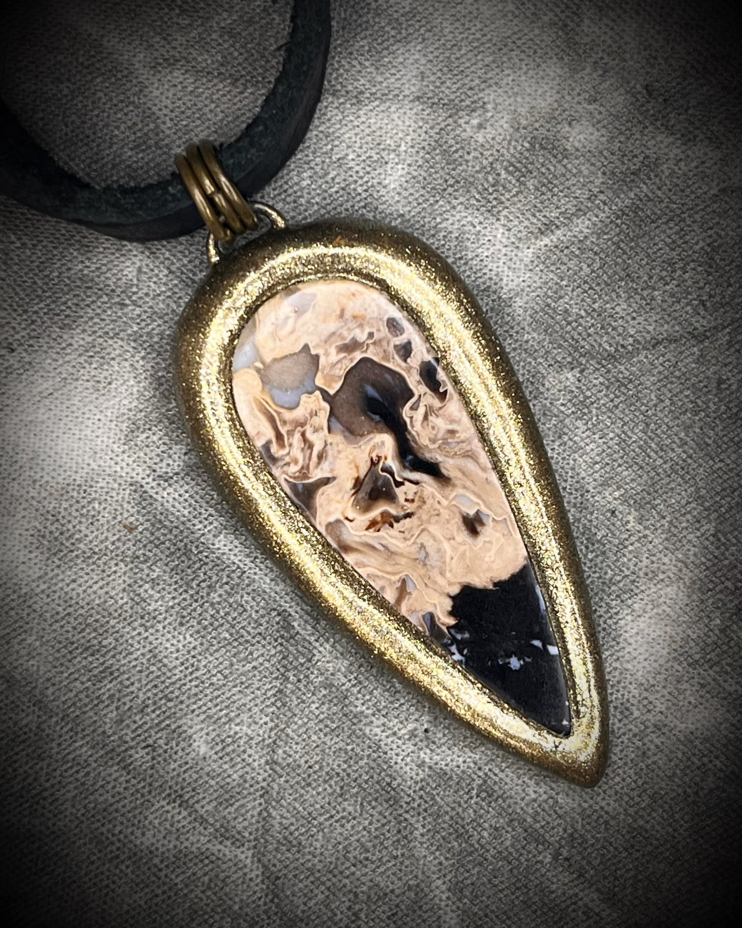 Petrified palm root necklace, teardrop shaped and set in a gold finish. Fossilized wood pendant hung from black leather for a protective and grounding vibe. 