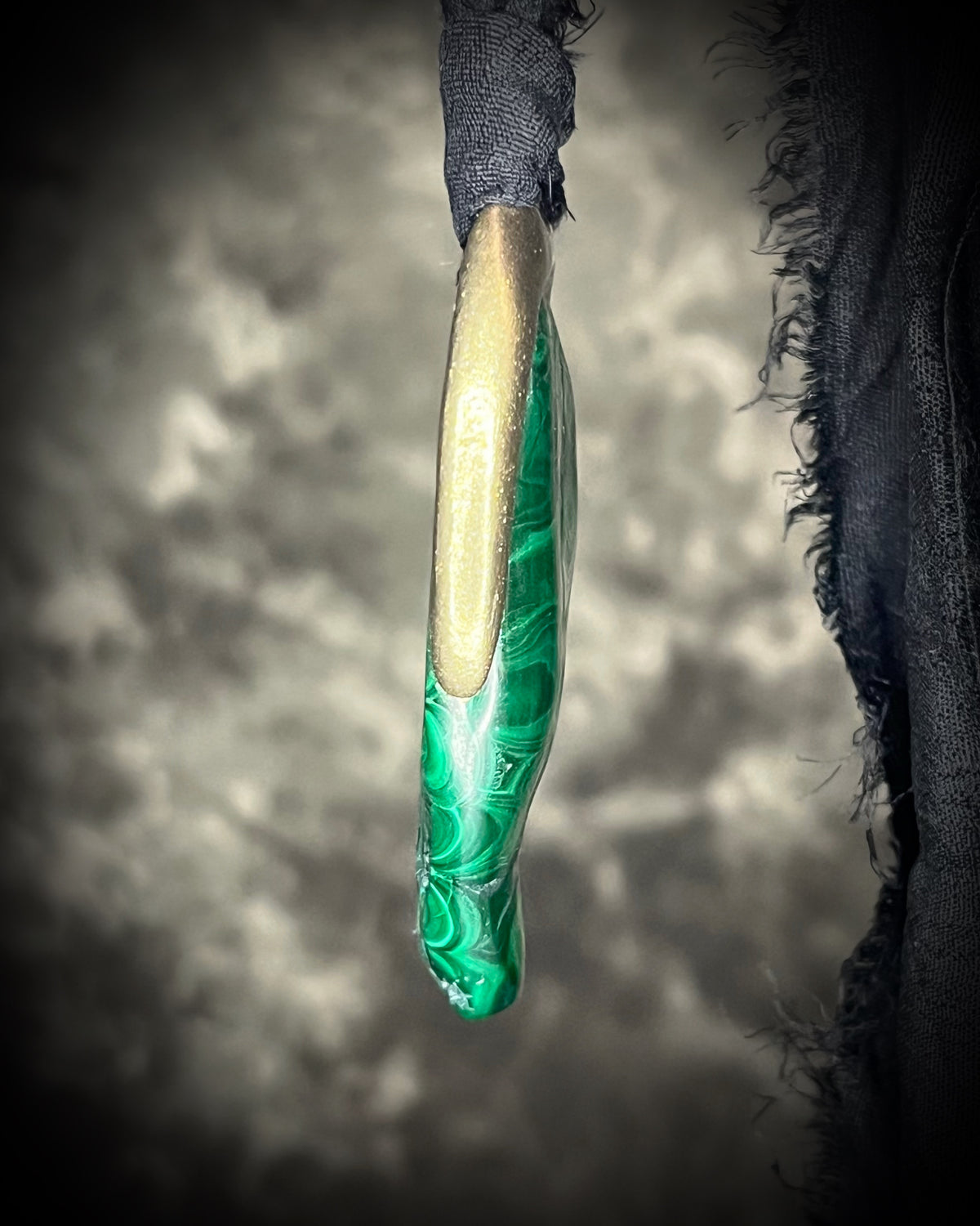 Polished malachite freeform crystal with natural green bands in a sculptural gold-finish talisman setting on black recycled silk, handmade by Become Spellbound in Baltimore, Maryland.