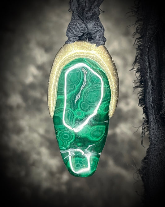 Polished malachite freeform crystal with natural green bands in a sculptural gold-finish talisman setting on black recycled silk, handmade by Become Spellbound in Baltimore, Maryland.