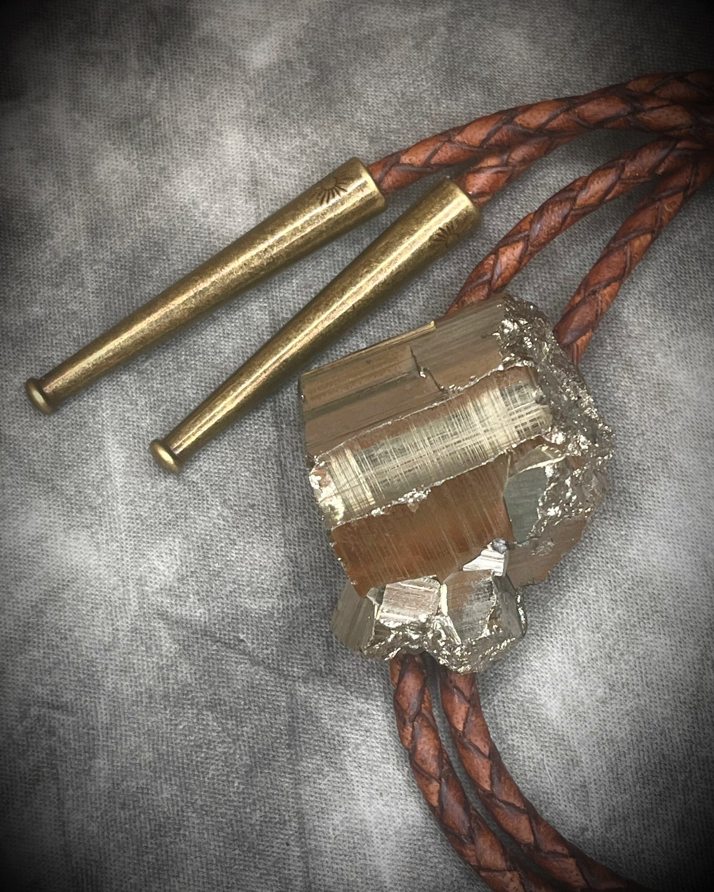 Pyrite bolo tie necklace on brown leather with gold tone finish and brass bolo tips, Western style men’s statement jewelry with natural pyrite crystal, handmade in Baltimore Maryland.