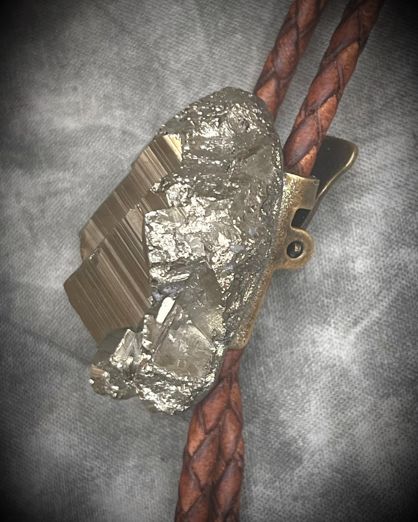 Pyrite bolo tie necklace on brown leather with gold tone finish and brass bolo tips, Western style men’s statement jewelry with natural pyrite crystal, handmade in Baltimore Maryland, Side view.