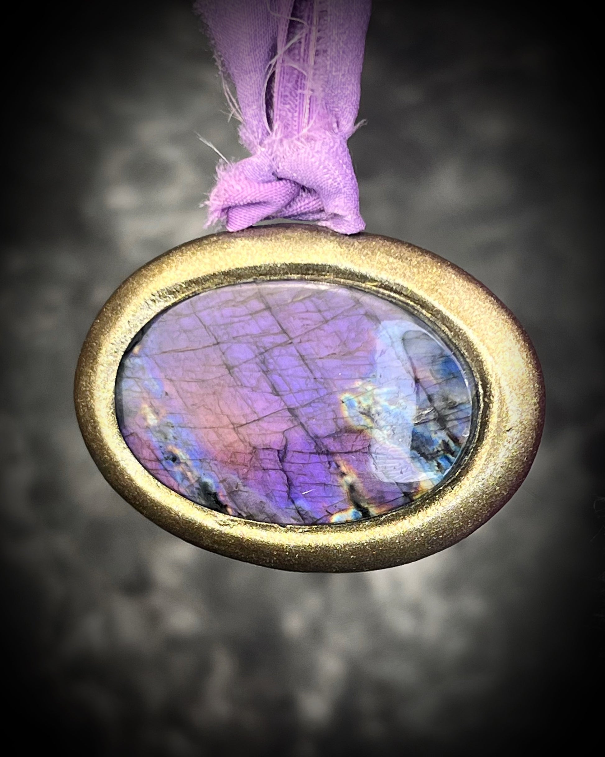 Rare purple flash labradorite talisman with sculpted gold finish and lilac recycled silk ties, handmade by Become Spellbound, Baltimore Magazine Best of Baltimore 2026 Jewelry winner.