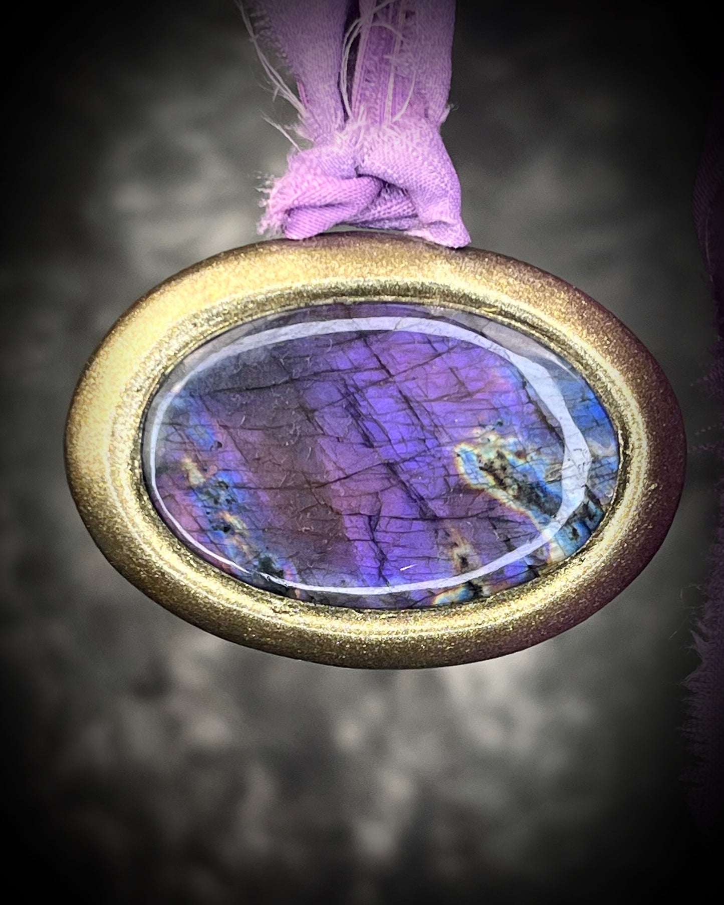 Rare purple flash labradorite talisman with sculpted gold finish and lilac recycled silk ties, handmade by Become Spellbound, Baltimore Magazine Best of Baltimore 2026 Jewelry winner.