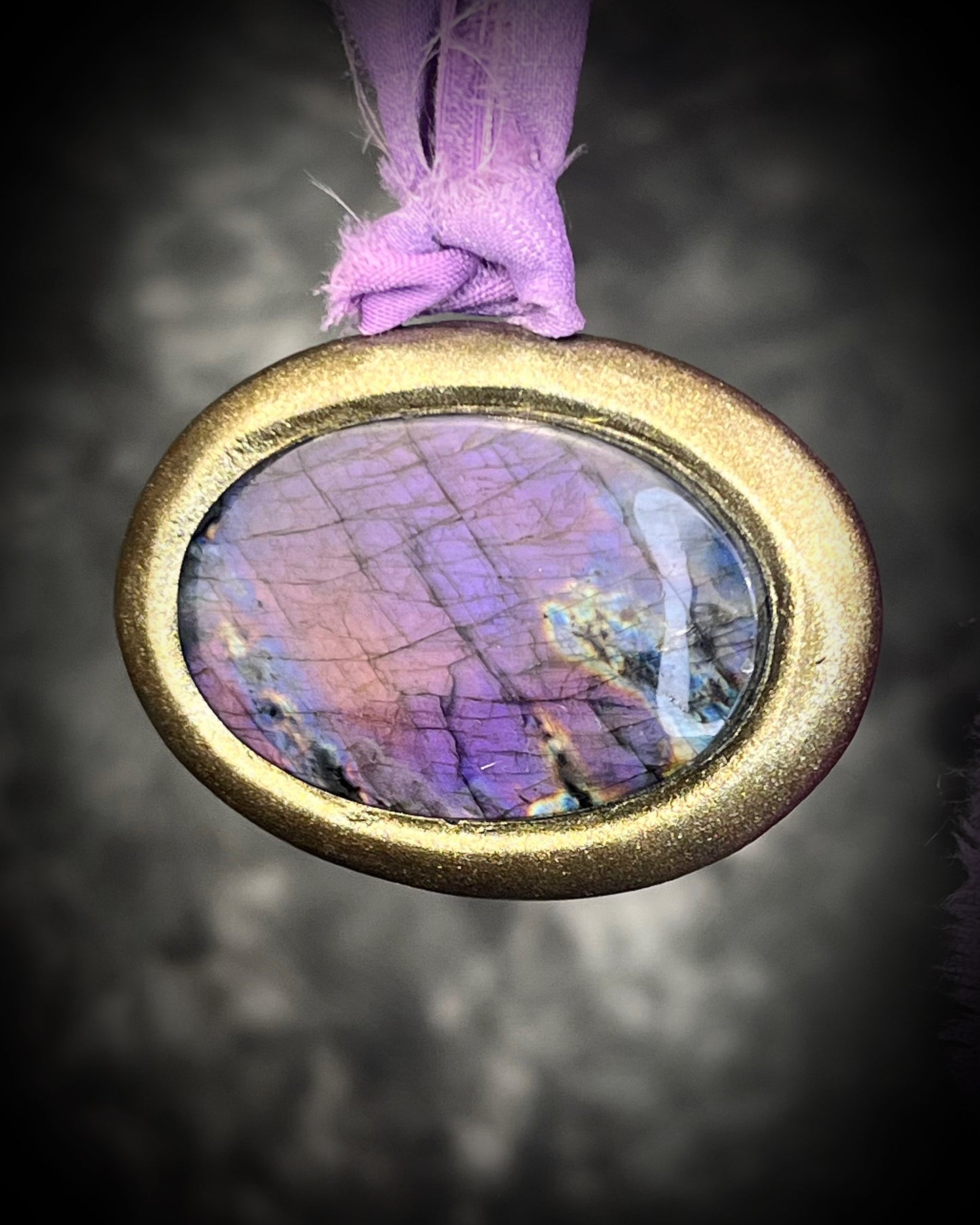 Rare purple flash labradorite talisman with sculpted gold finish and lilac recycled silk ties, handmade by Become Spellbound, Baltimore Magazine Best of Baltimore 2026 Jewelry winner.