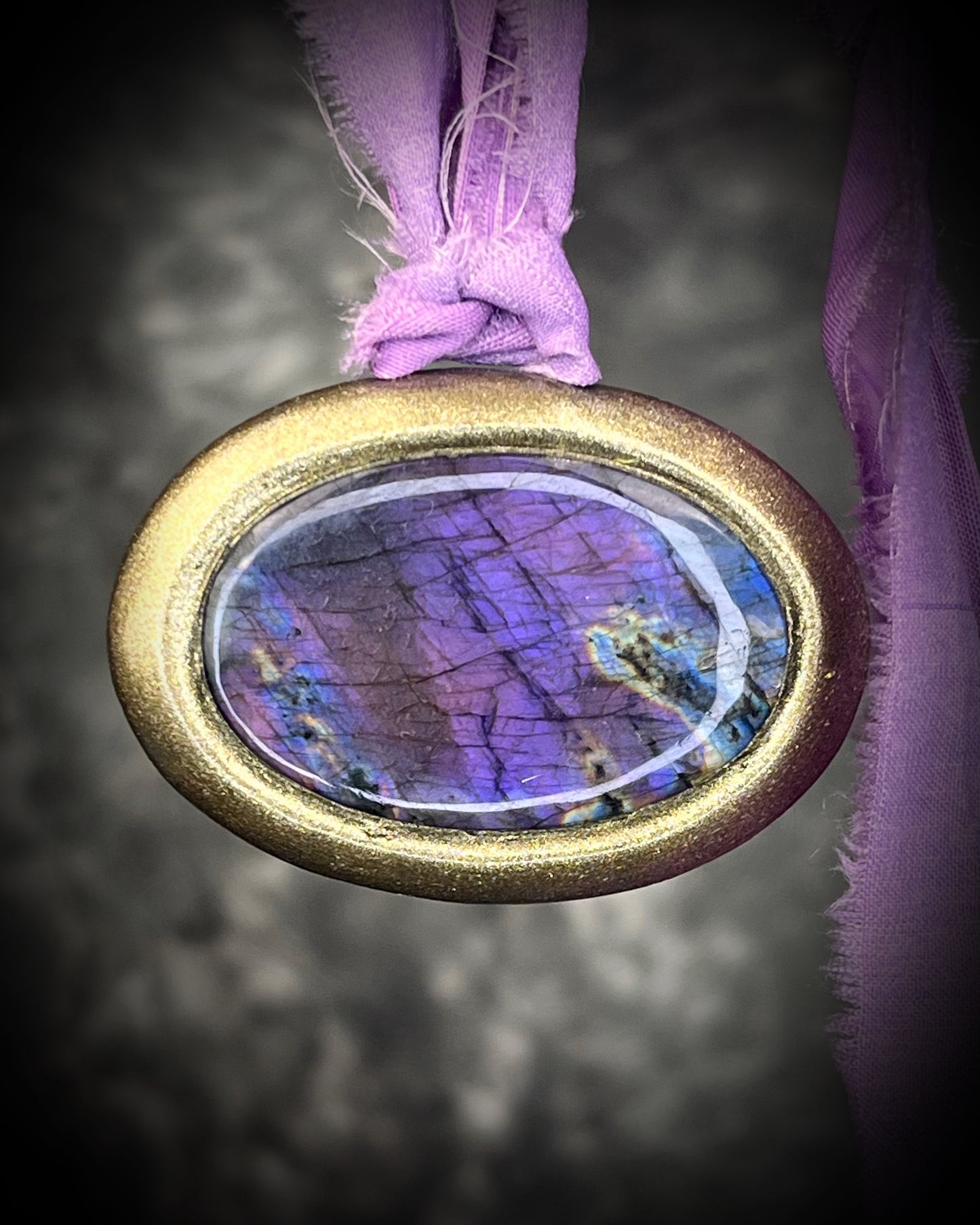 Rare purple flash labradorite talisman with sculpted gold finish and lilac recycled silk ties, handmade by Become Spellbound, Baltimore Magazine Best of Baltimore 2026 Jewelry winner.