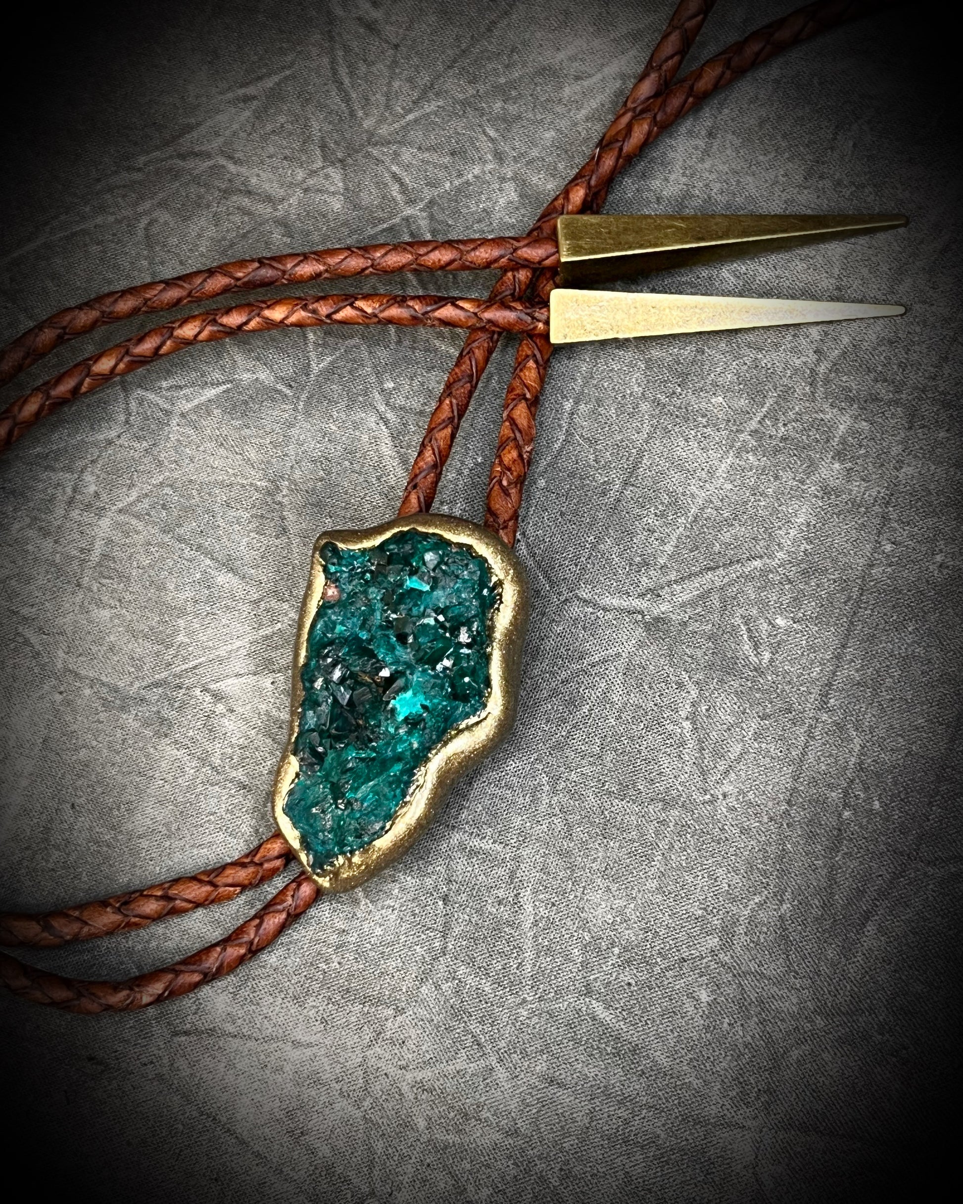 Raw Dioptase teal colored gemstone Bolo tie set in a gold finish and mounted on earthy brown leather. A talisman for heart chakra healing, crystal jewelry for him. Western 2026 jewelry trend bolo. 