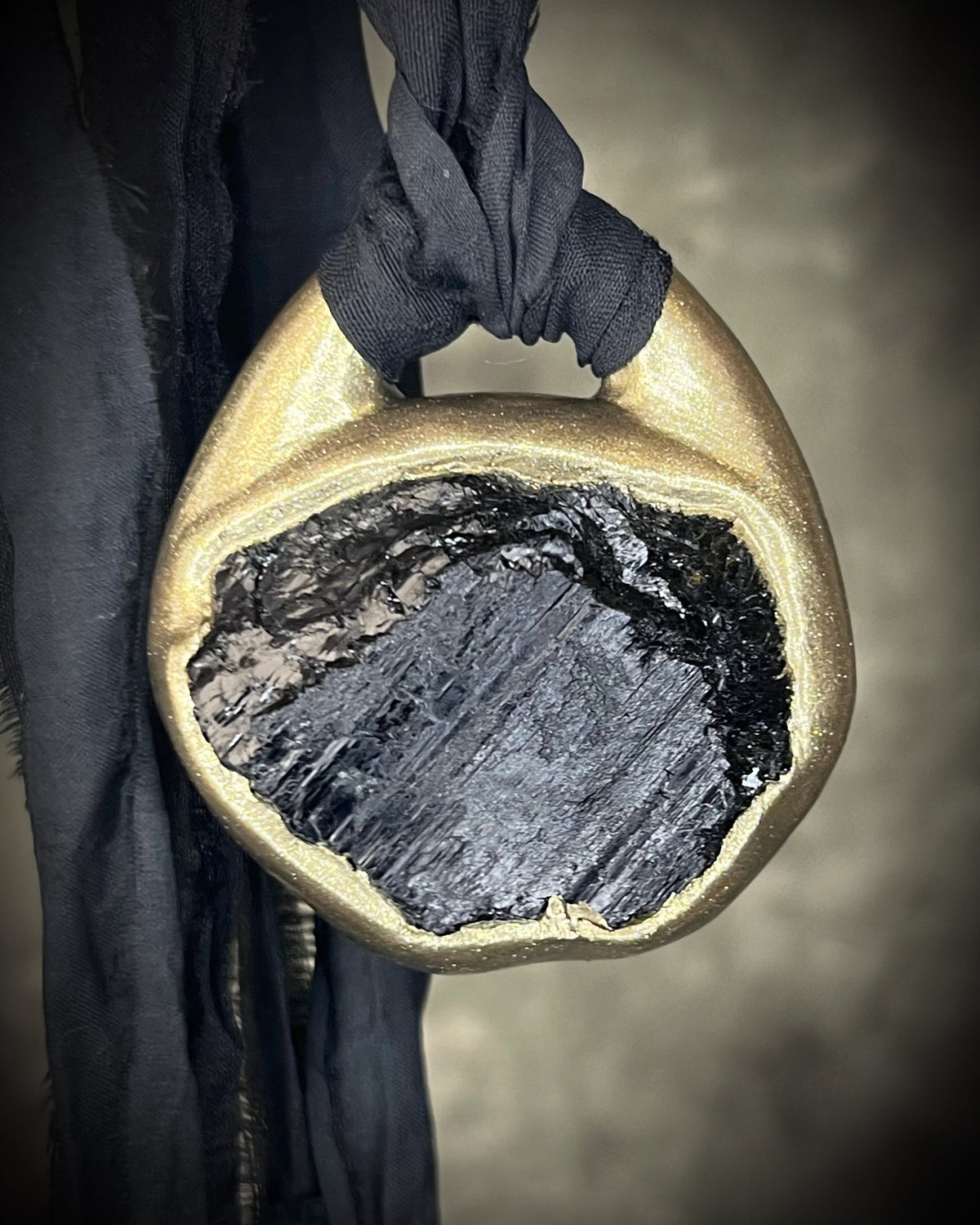 Raw black tourmaline chunk protection talisman with gold finish on black recycled silk, handmade by Become Spellbound in Baltimore, Maryland.