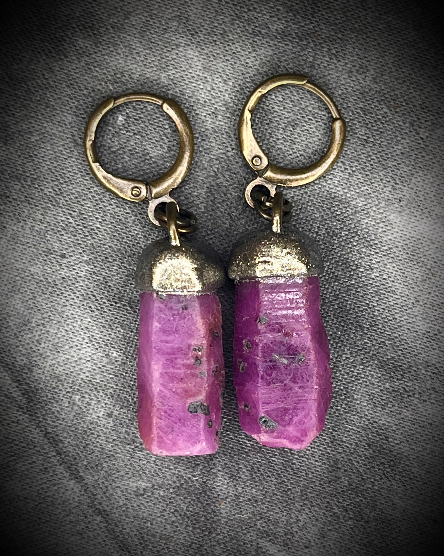 Raw ruby crystal earrings in gold finish on hypoallergenic brass huggie hooks, July birthstone gemstone jewelry handmade in Baltimore Maryland. Closeup.