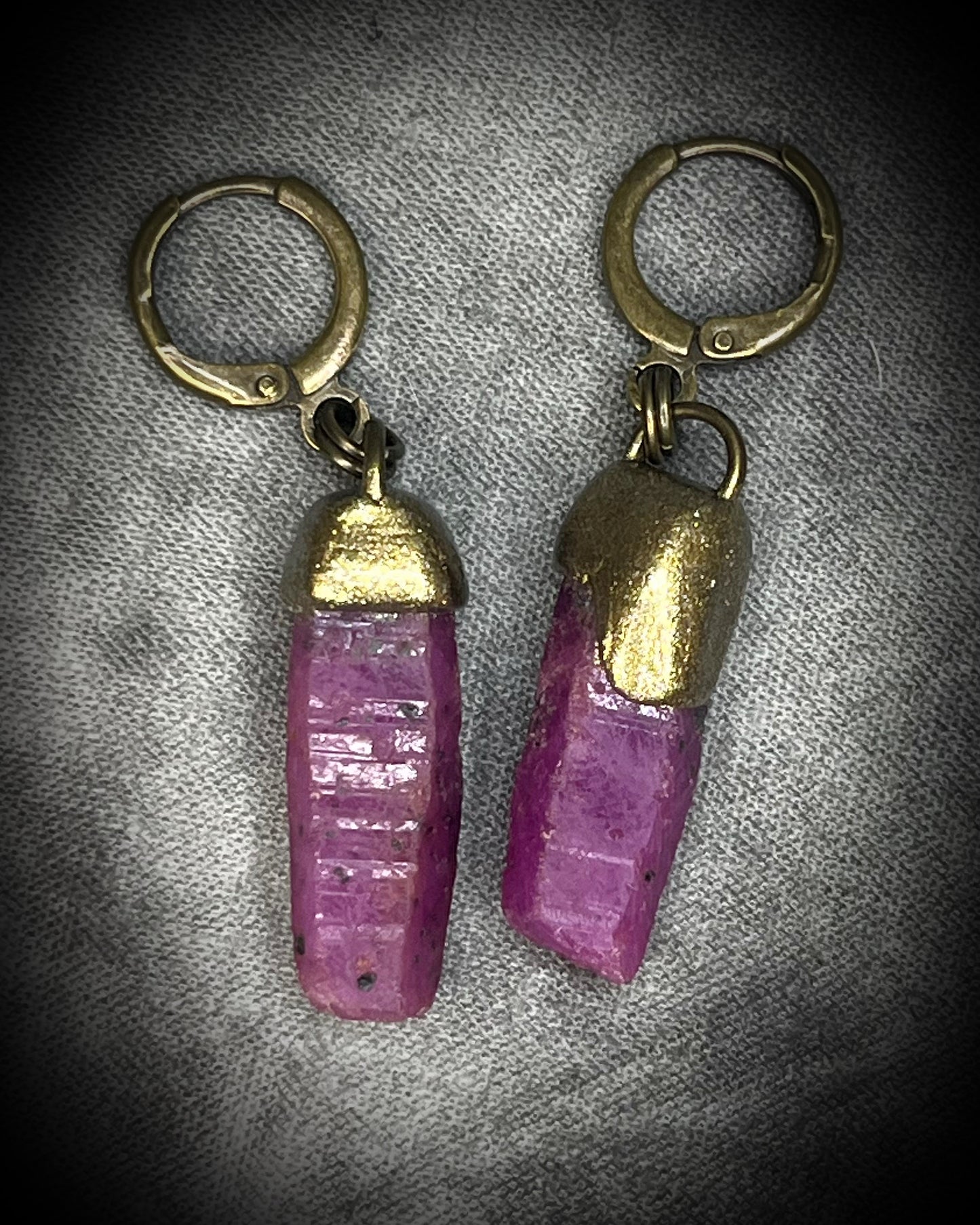 Raw ruby crystal earrings in gold finish on hypoallergenic brass huggie hooks, July birthstone gemstone jewelry handmade in Baltimore Maryland. Closeup.