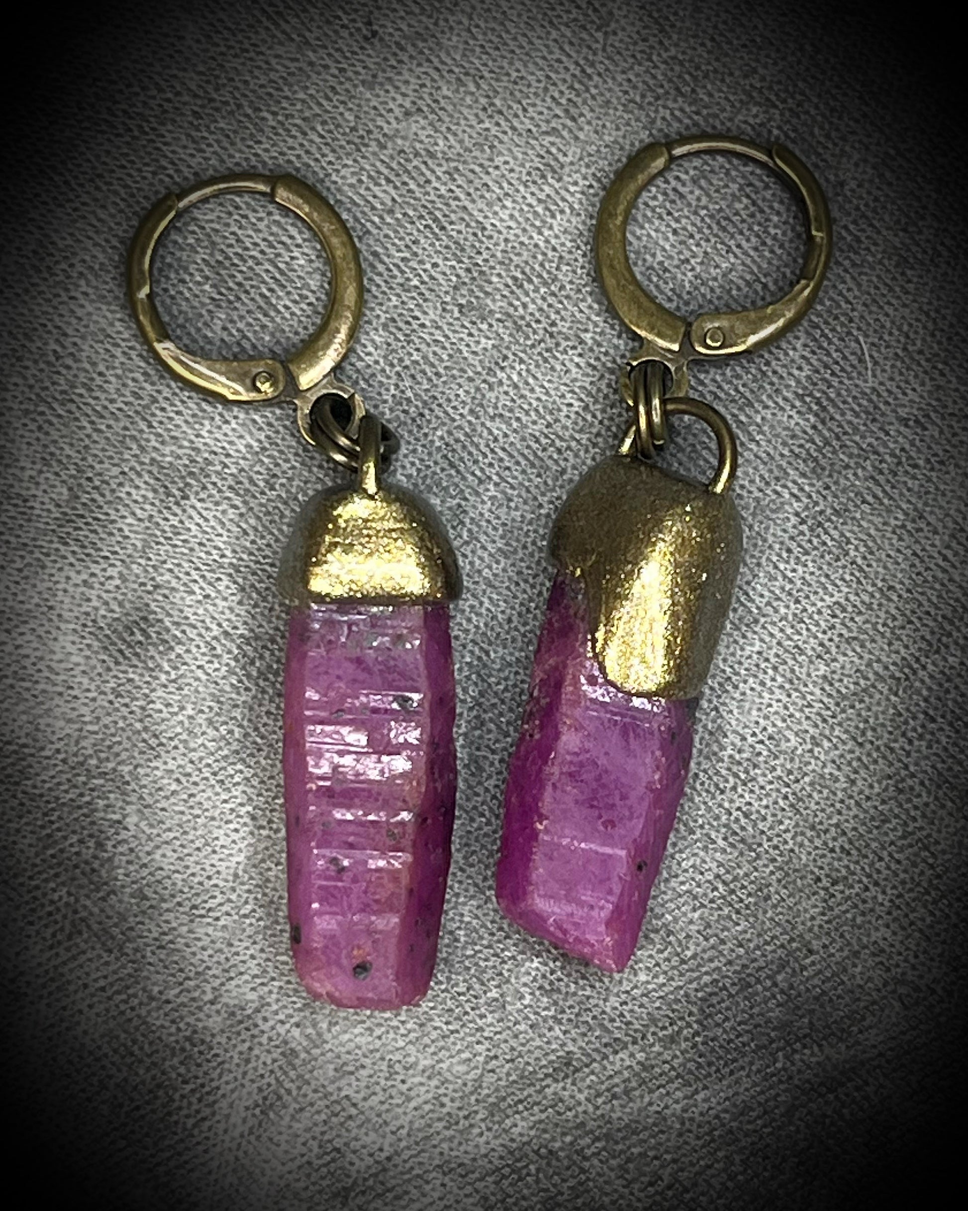 Raw ruby crystal earrings in gold finish on hypoallergenic brass huggie hooks, July birthstone gemstone jewelry handmade in Baltimore Maryland. Closeup.