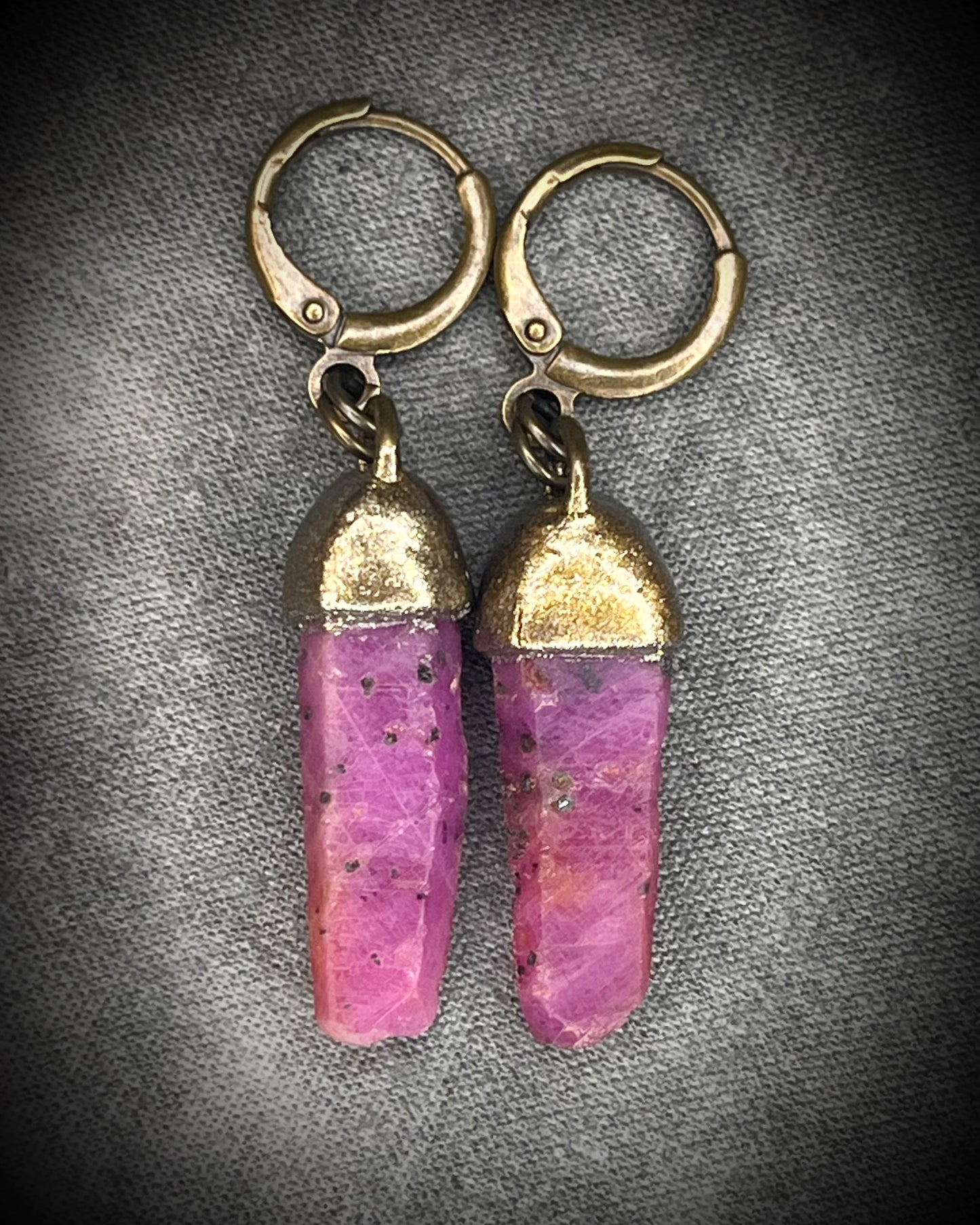 Raw ruby crystal earrings in gold finish on hypoallergenic brass huggie hooks, July birthstone gemstone jewelry handmade in Baltimore Maryland. Closeup.