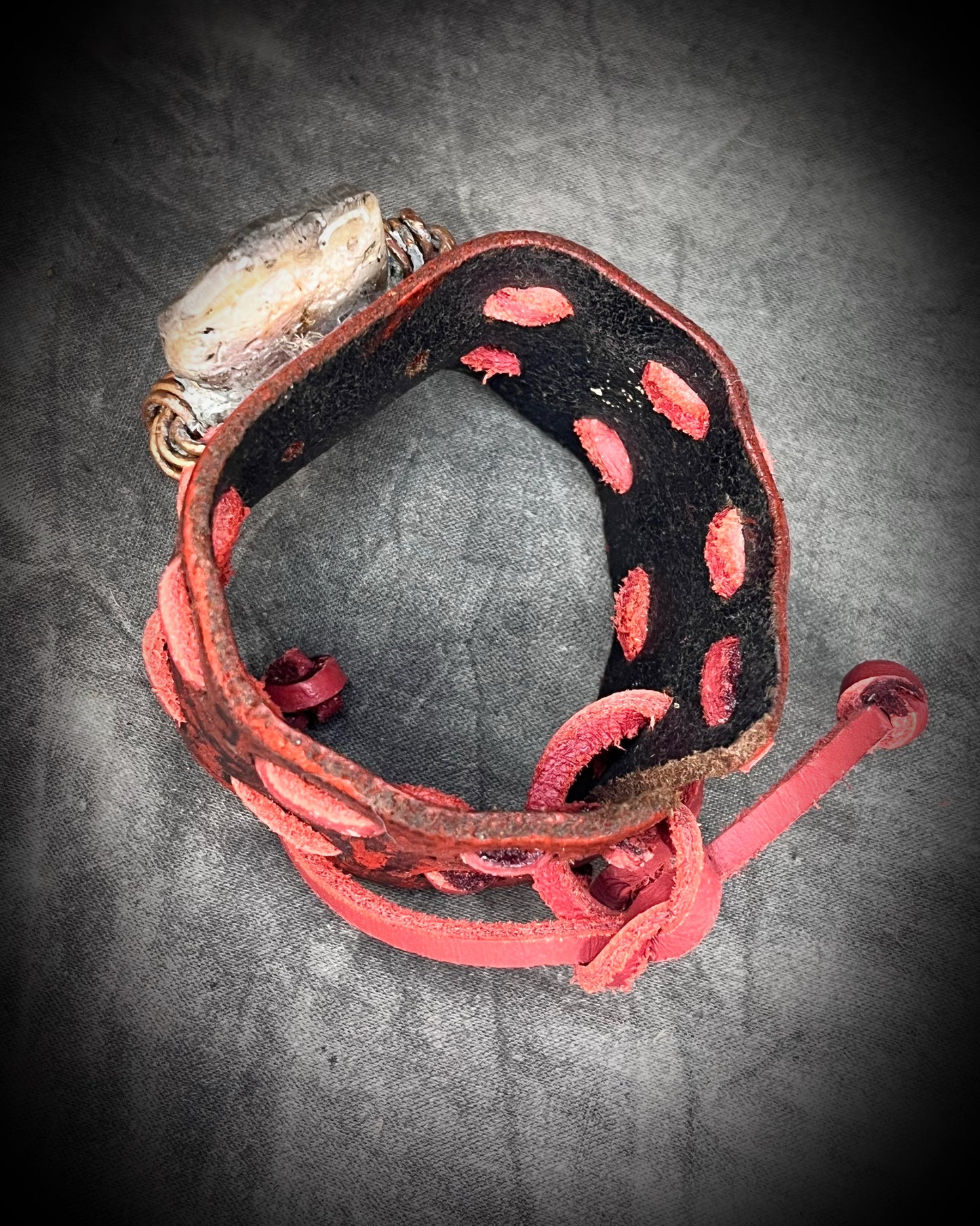 Red leather cuff hand-stitched and finished with a huge abalone mother of pearl seashell. Adjustable tie-on leather cords complete this bold, unisex statement piece.
