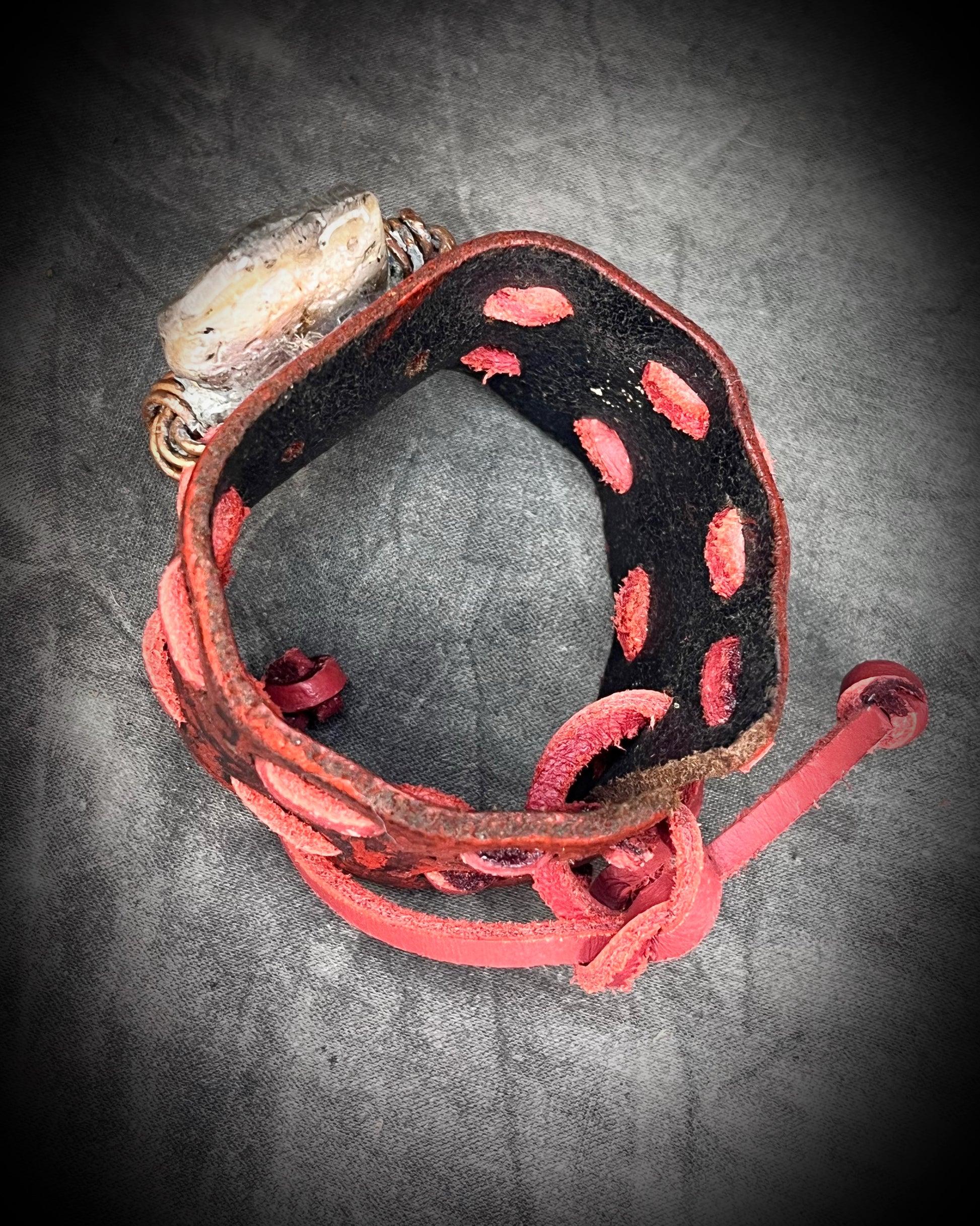 Red leather cuff hand-stitched and finished with a huge abalone mother of pearl seashell. Adjustable tie-on leather cords complete this bold, unisex statement piece.