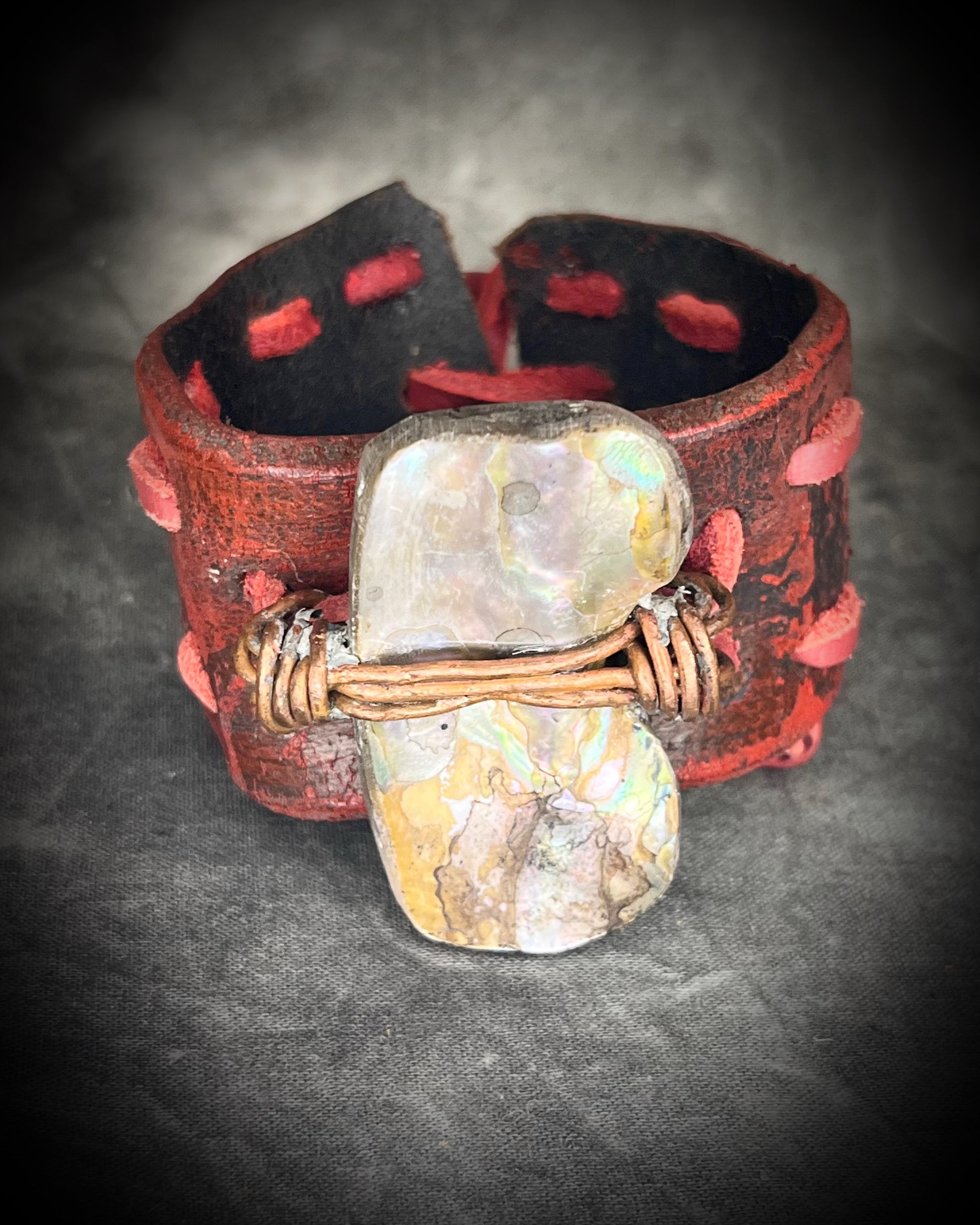 Red leather cuff hand-stitched and finished with a huge abalone mother of pearl seashell. Adjustable tie-on leather cords complete this bold, unisex statement piece.