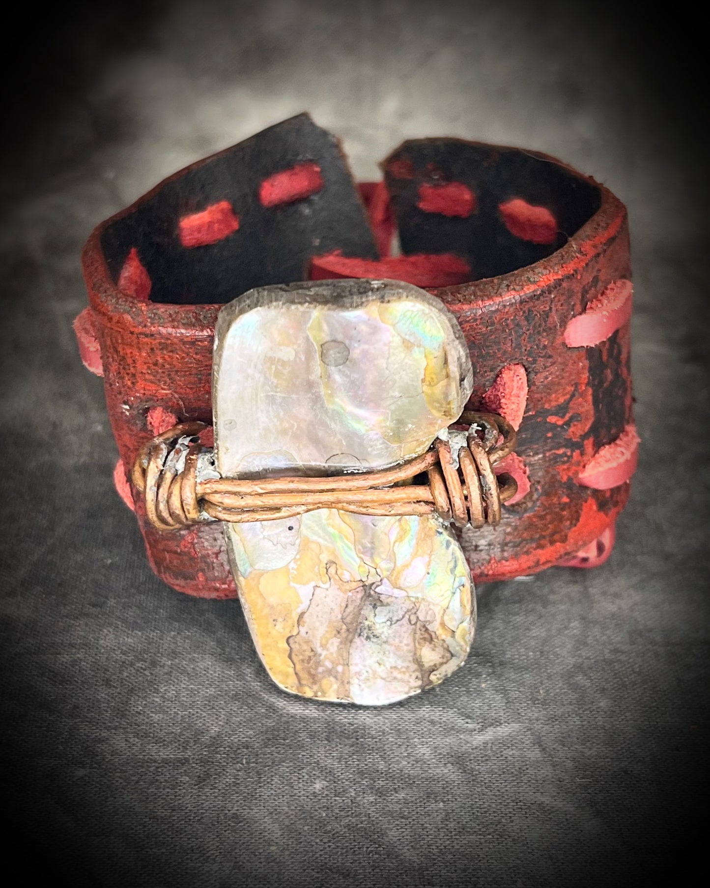 Red leather cuff hand-stitched and finished with a huge abalone mother of pearl seashell. Adjustable tie-on leather cords complete this bold, unisex statement piece.