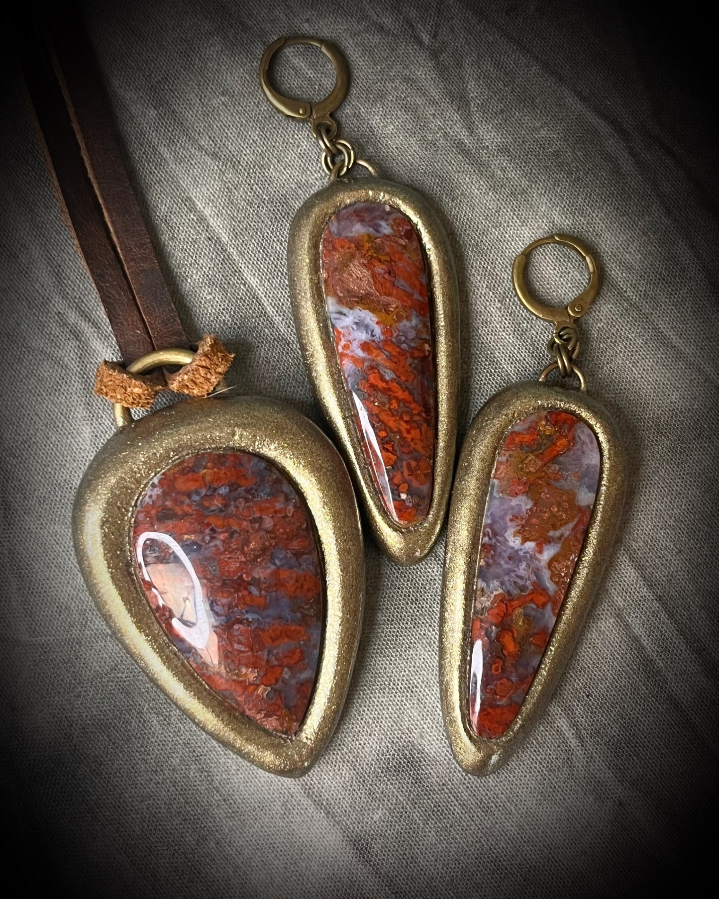 Red moss agate pendant in a gold finish, handmade and hung from brown earthy leather. Empowering and manifestation talisman for 2026 year of the fire horse. Shown here with matching gold huggie dangle earrings.