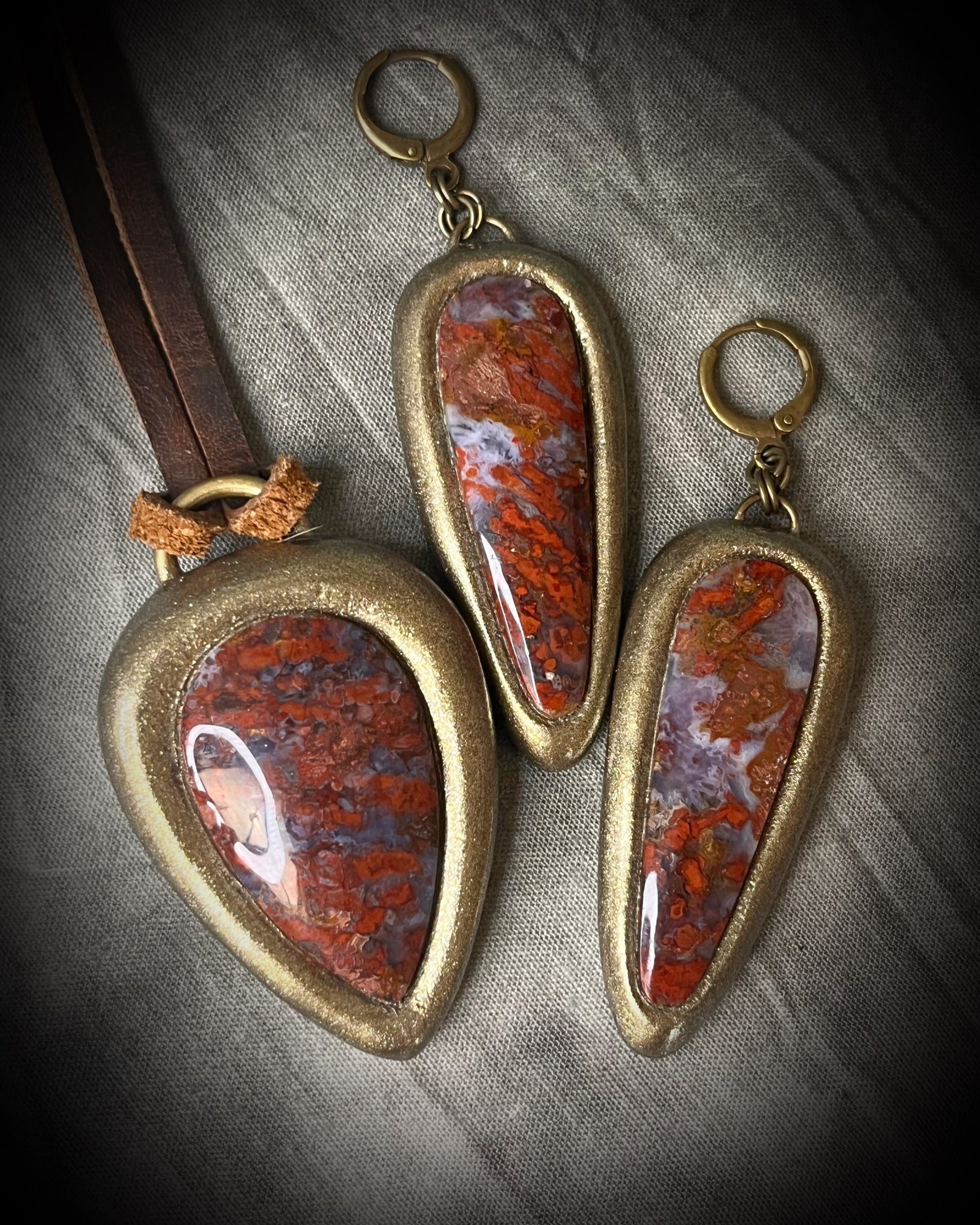 Red moss agate pendant in a gold finish, handmade and hung from brown earthy leather. Empowering and manifestation talisman for 2026 year of the fire horse. Shown here with matching gold huggie dangle earrings.