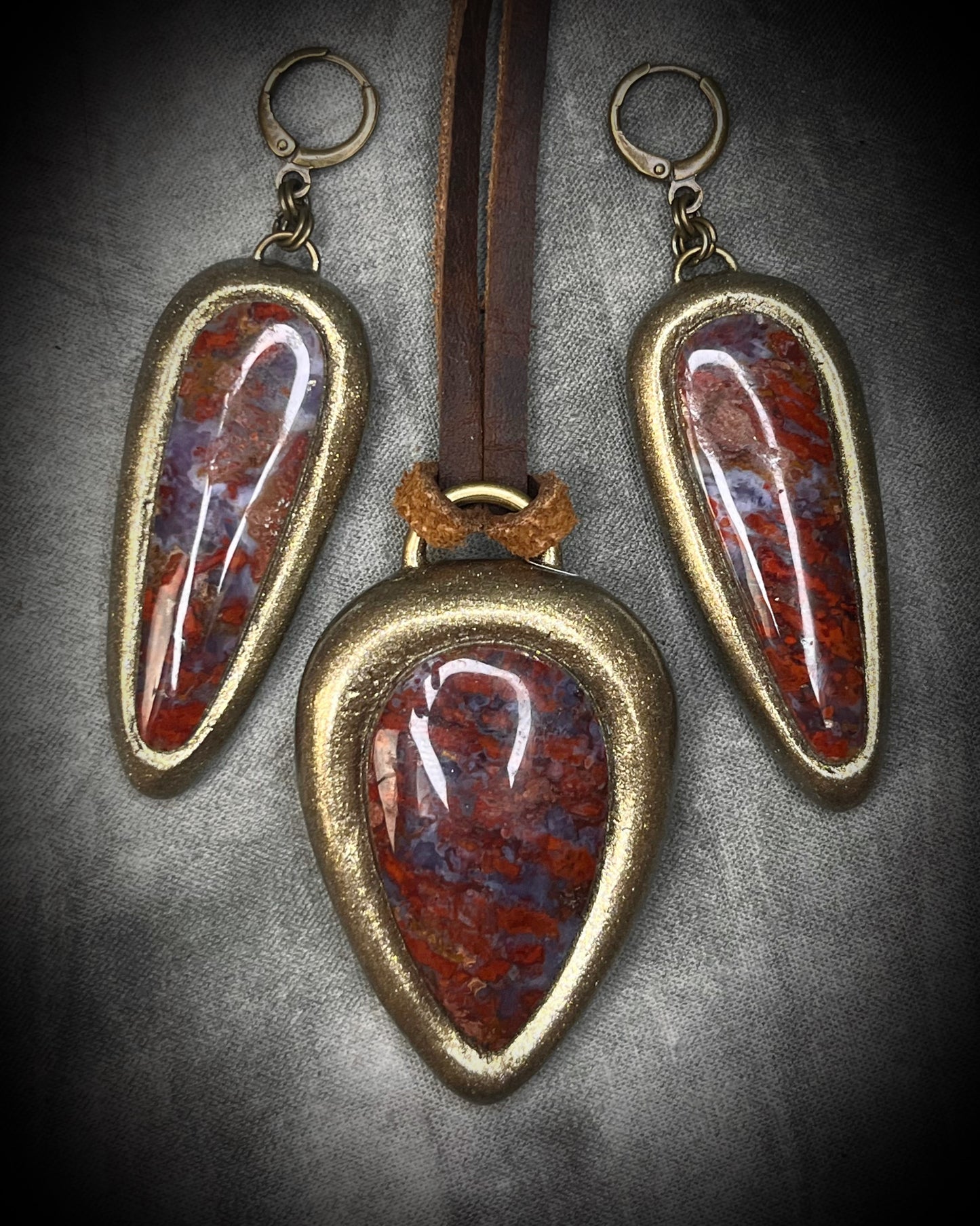 Red moss agate pendant in a gold finish, handmade and hung from brown earthy leather. Empowering and manifestation talisman for 2026 year of the fire horse. Shown here with matching gold huggie dangle earrings.