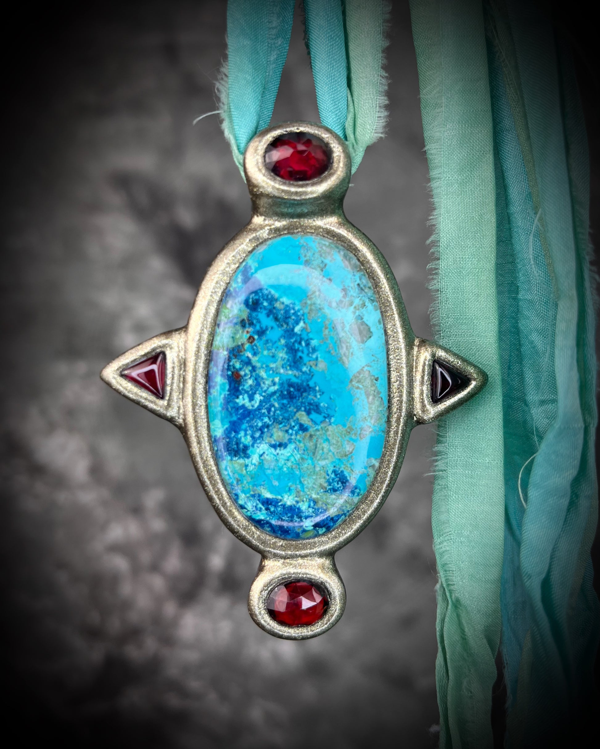 Regal handmade chrysocolla pendant adorned with 4 sparkling garnets in the cardinal directions. The Empress Talisman fit for a queen, gold finish artisanal pendant on soft aqua recycled silk. Statement jewelry for her. 