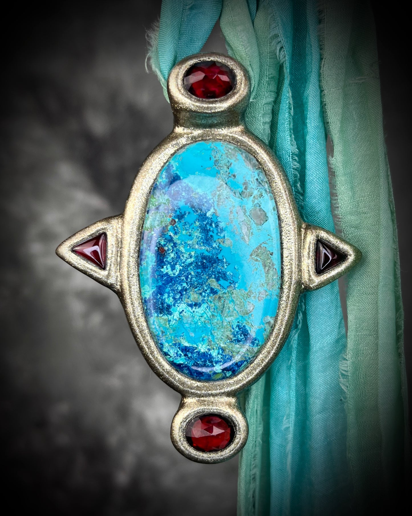 Regal handmade chrysocolla pendant adorned with 4 sparkling garnets in the cardinal directions. The Empress Talisman fit for a queen, gold finish artisanal pendant on soft aqua recycled silk. Statement jewelry for her. 