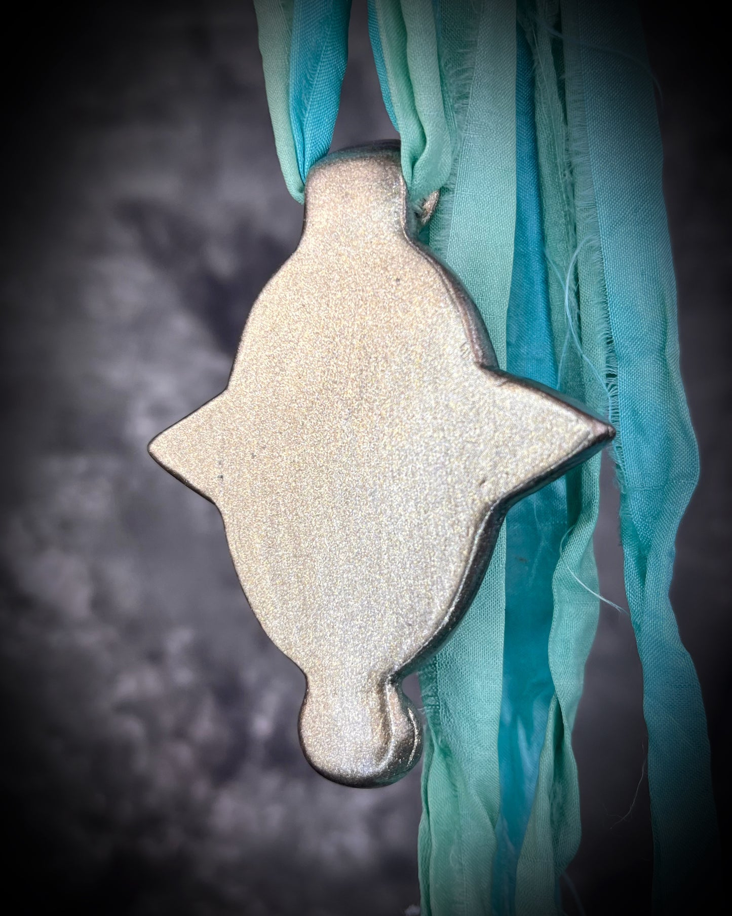 Regal handmade chrysocolla pendant adorned with 4 sparkling garnets in the cardinal directions. The Empress Talisman fit for a queen, gold finish artisanal pendant on soft aqua recycled silk. Statement jewelry for her. Back view.