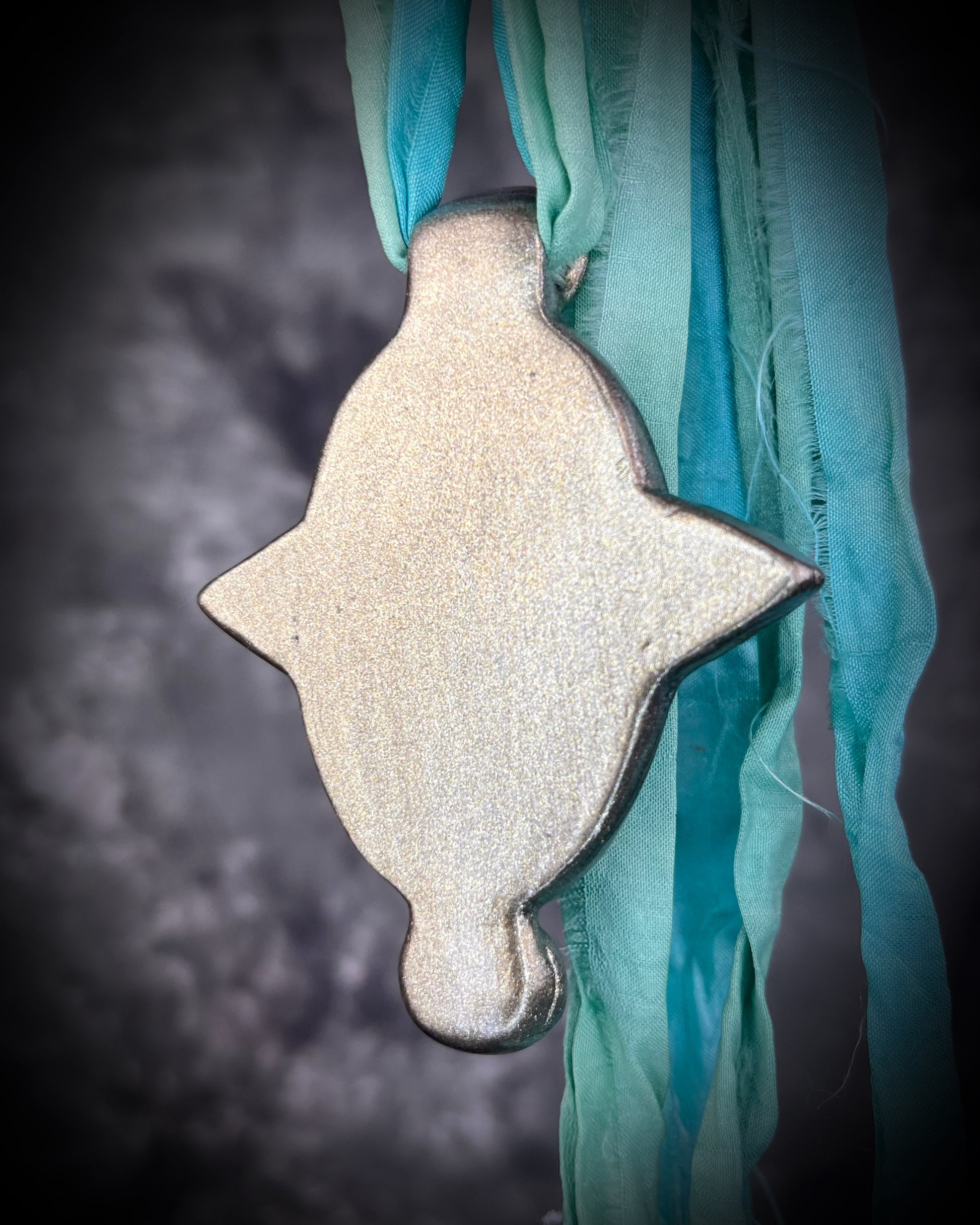 Regal handmade chrysocolla pendant adorned with 4 sparkling garnets in the cardinal directions. The Empress Talisman fit for a queen, gold finish artisanal pendant on soft aqua recycled silk. Statement jewelry for her. Back view.