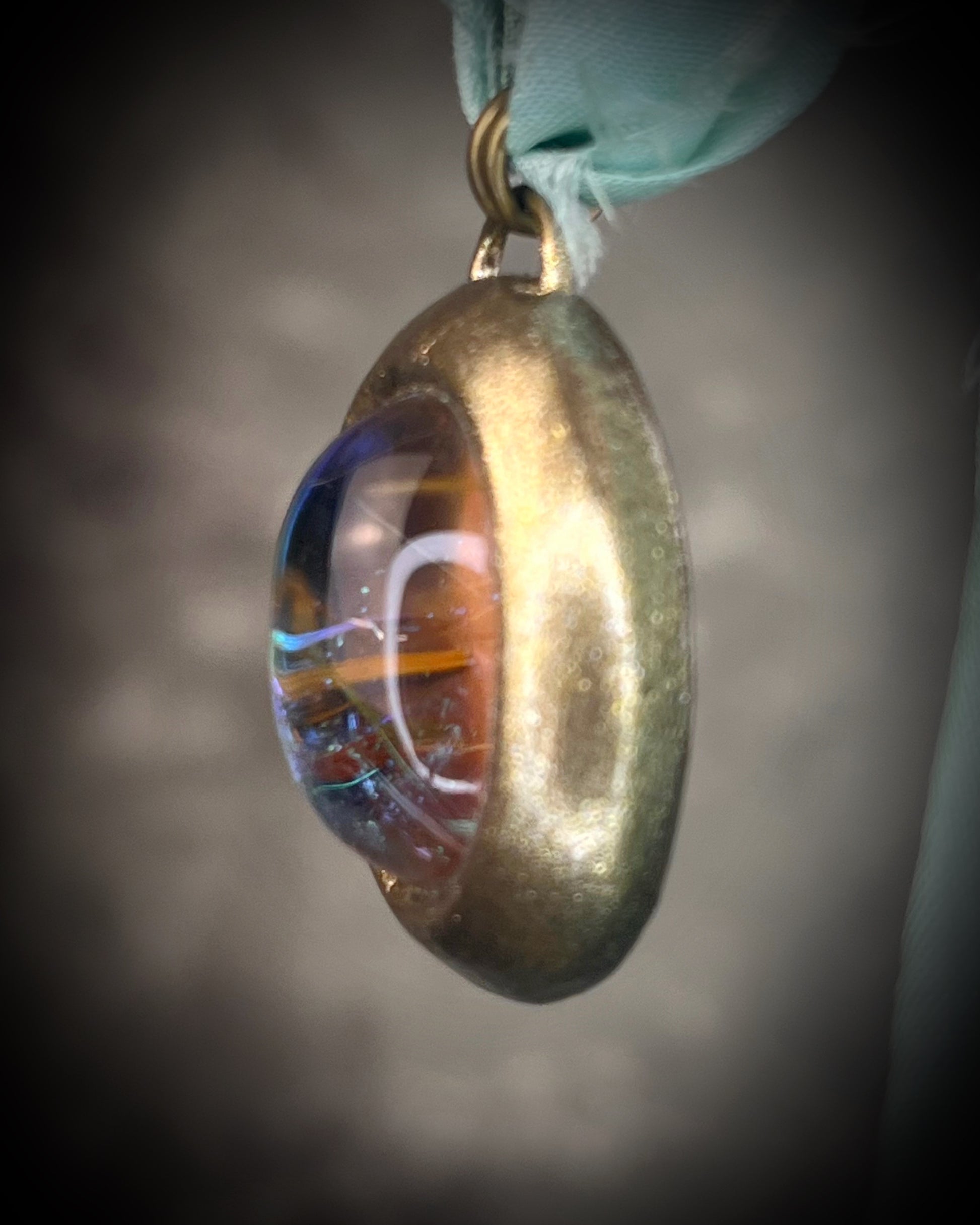 Rutilated quartz crystal talisman with sculpted gold finish, luminous green opalescent color shift, and aqua recycled silk ties. Handmade by Become Spellbound.