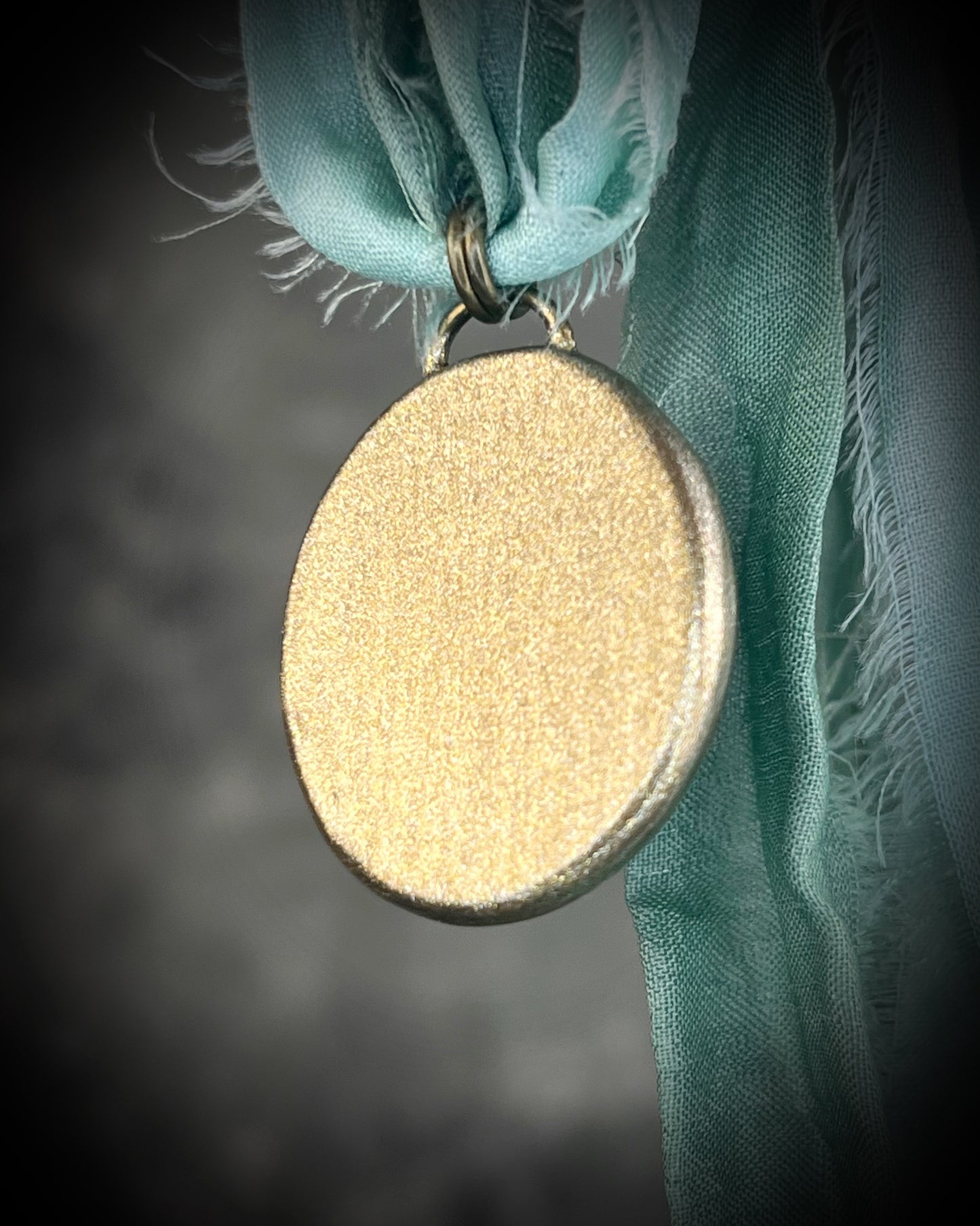 Rutilated quartz crystal talisman with sculpted gold finish, luminous green opalescent color shift, and aqua recycled silk ties. Handmade by Become Spellbound.