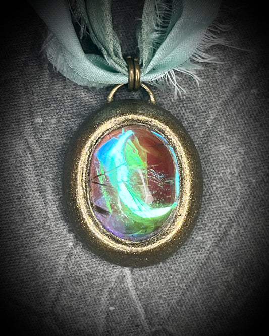 Rutilated quartz crystal talisman with sculpted gold finish, luminous green opalescent color shift, and aqua recycled silk ties. Handmade by Become Spellbound.
