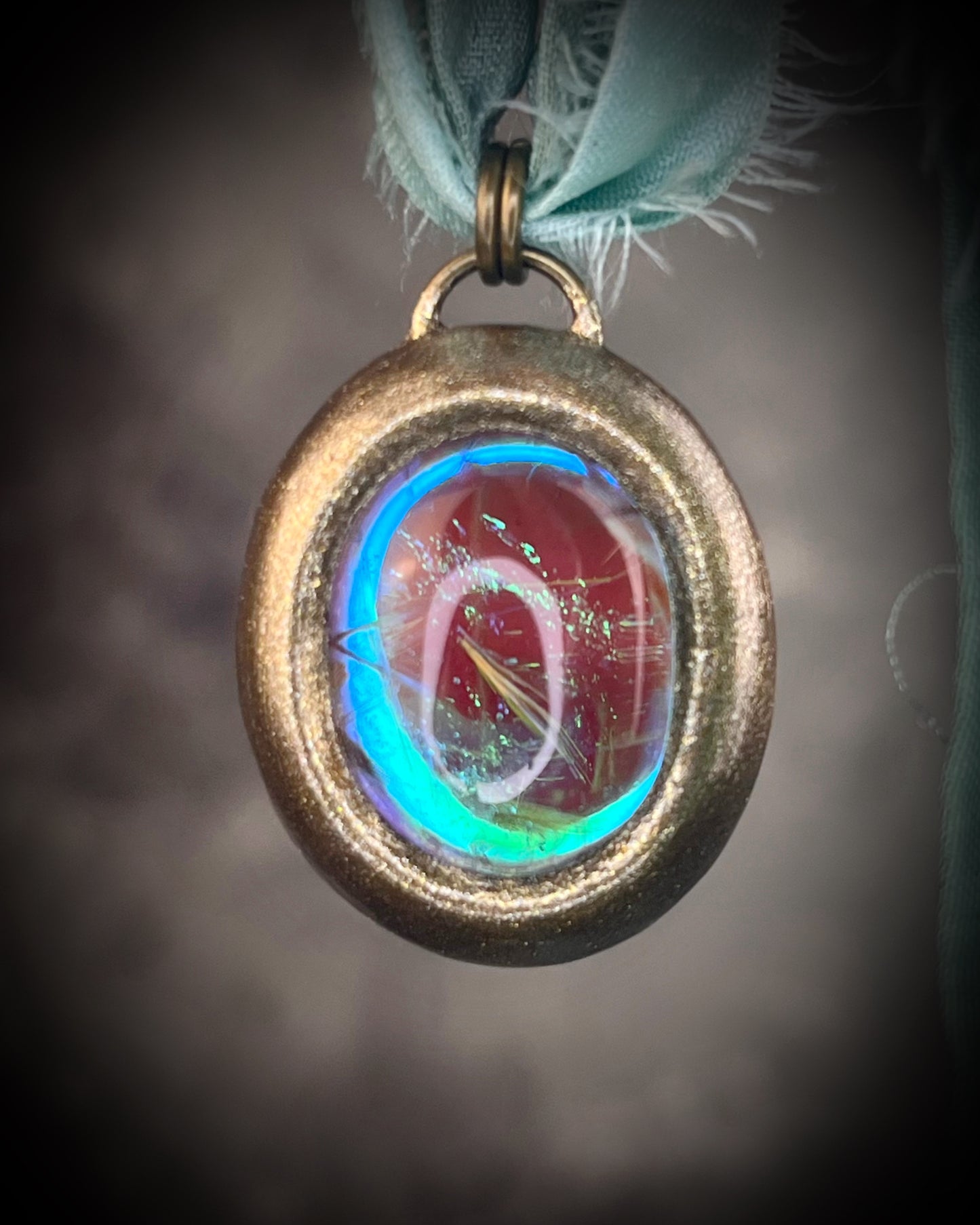 Rutilated quartz crystal talisman with sculpted gold finish, luminous green opalescent color shift, and aqua recycled silk ties. Handmade by Become Spellbound.