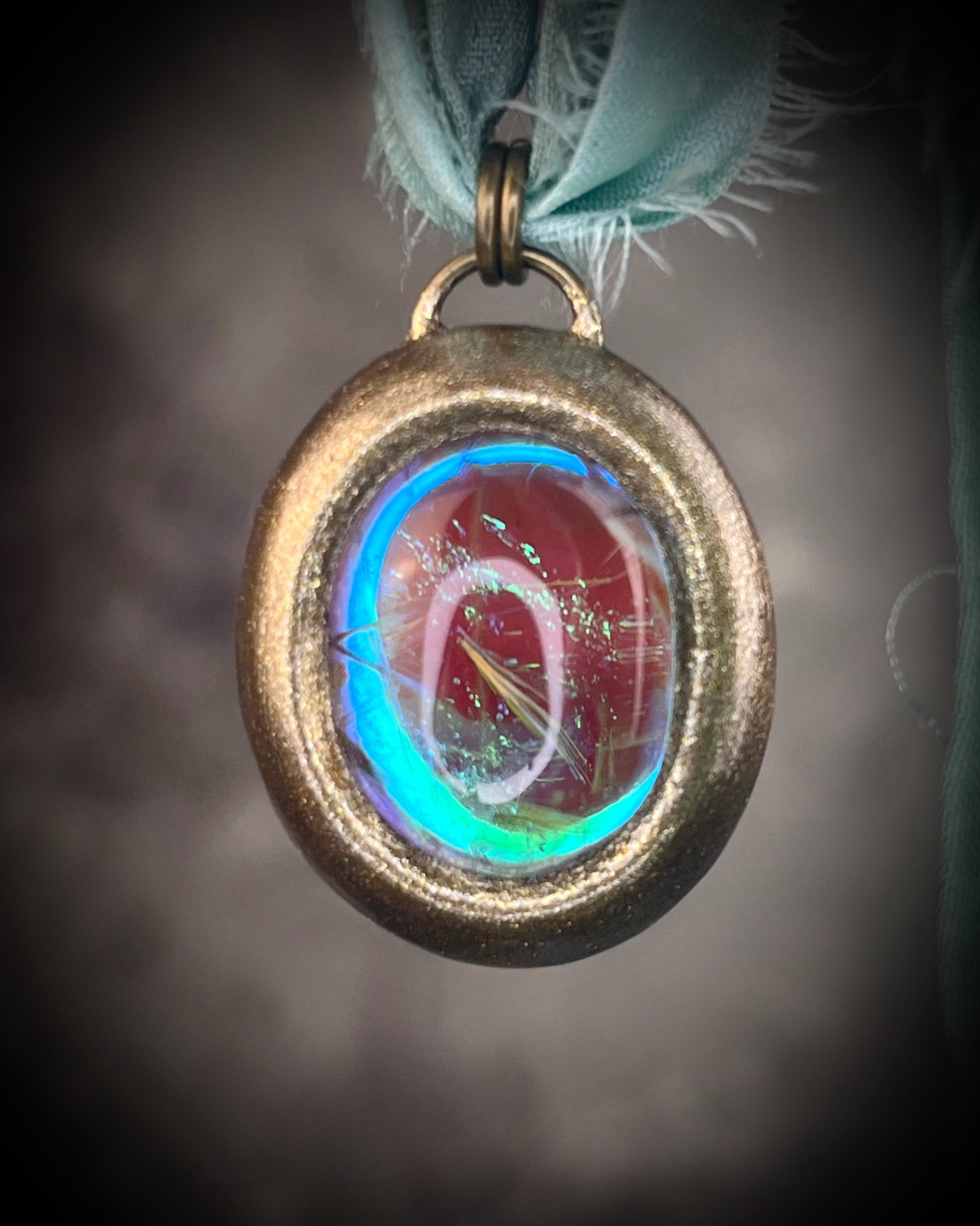 Rutilated quartz crystal talisman with sculpted gold finish, luminous green opalescent color shift, and aqua recycled silk ties. Handmade by Become Spellbound.