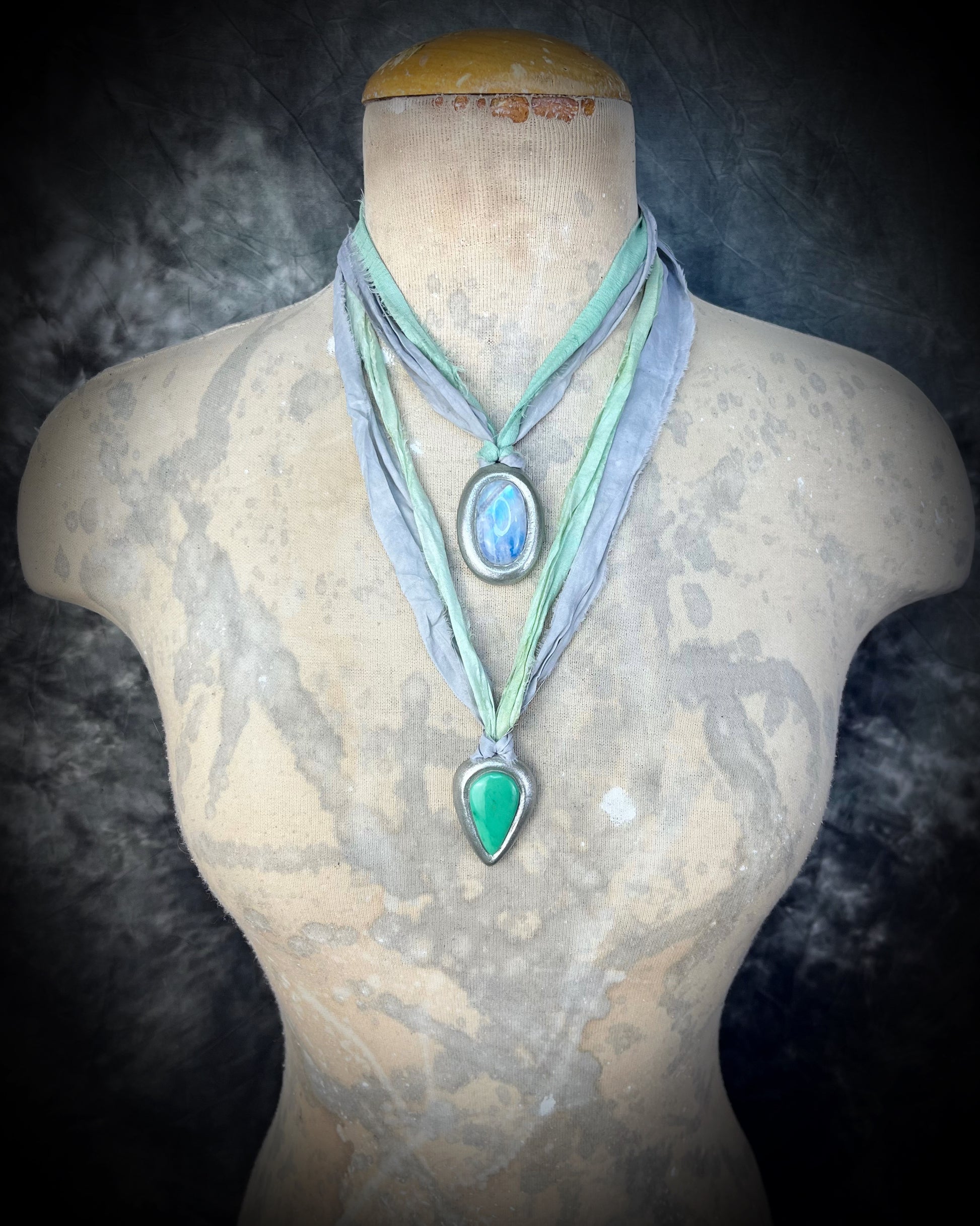Silver tone teardrop-shaped green chrysoprase gemstone necklace on grey and aqua recycled silks. Shown here modeled and layered with a silver rainbow moonstone pendant. Bohemian crystal healing handmade jewelry.