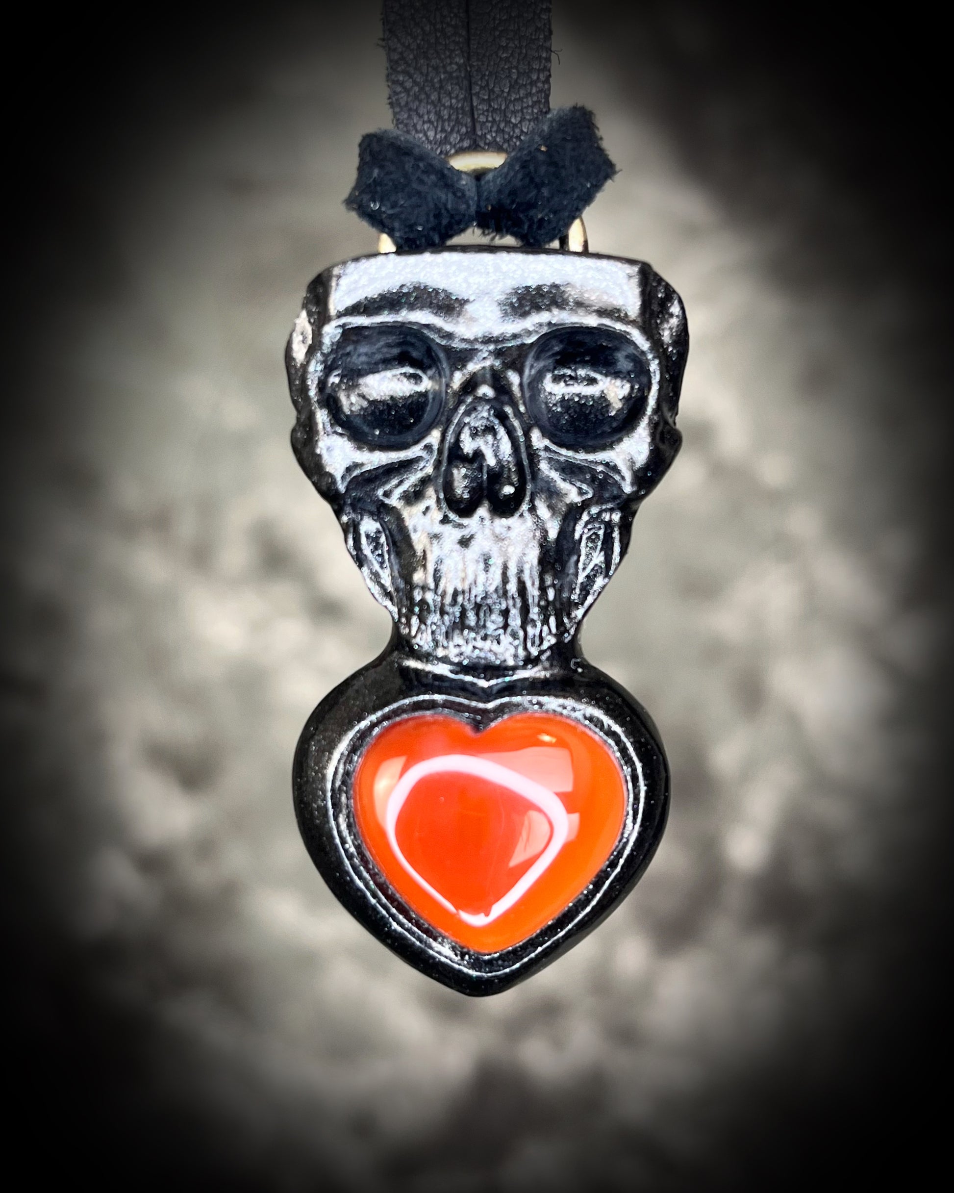 Skull-shaped pendant with a deep orange red carnelian heart shaped gemstone hung from black leather. Halloween jewelry for her, gothic jewelry gift for her. 