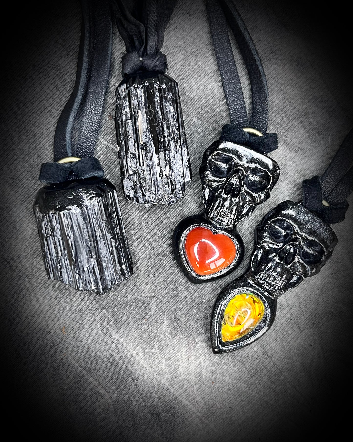 Several black tourmaling talismans and Skull-shaped pendants with a deep orange red carnelian heart shaped gemstones or golden citrine crystals all hung from black leather. Halloween jewelry for her, gothic jewelry gift for her. 