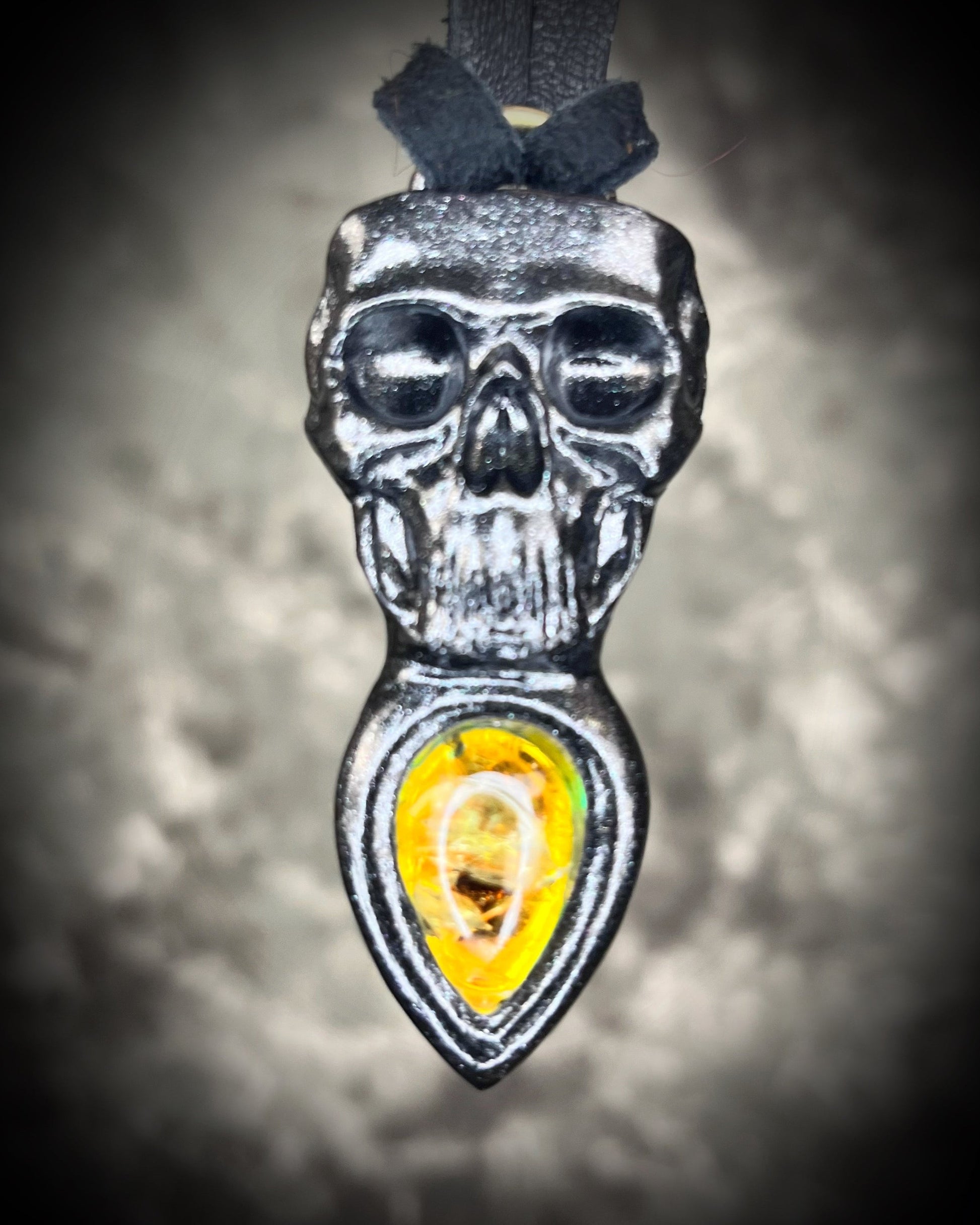 Skull-shaped pendant with a yellow fire citrine teardrop shaped gemstone on a dark background. Halloween jewelry for her, gothic jewelry gift for her. 