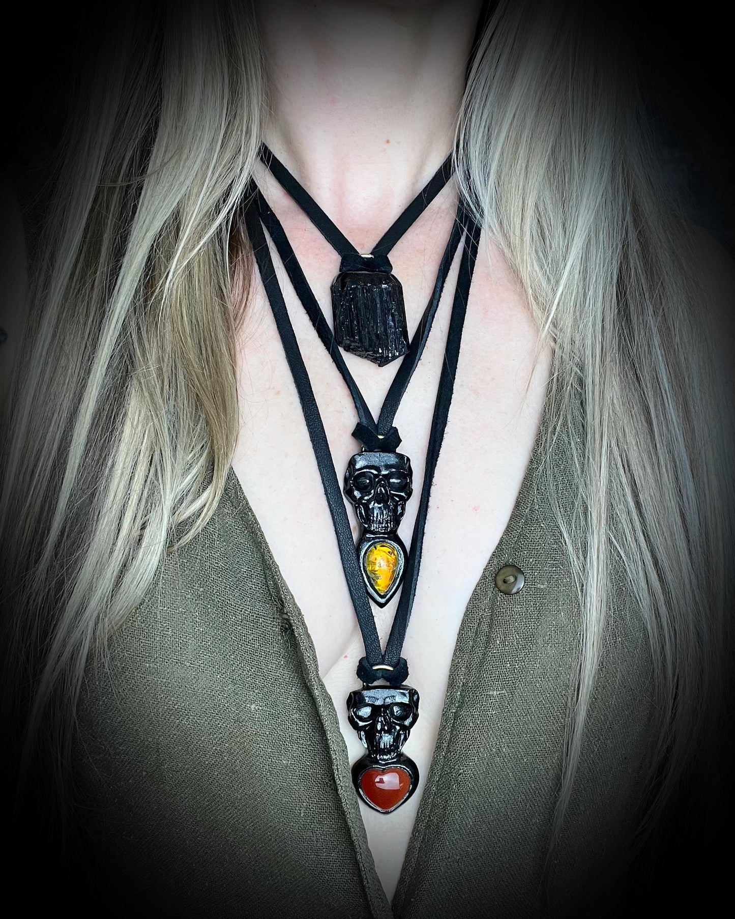 Skull-shaped pendant with a yellow fire citrine teardrop shaped gemstone on a dark background. Halloween jewelry for her, gothic jewelry gift for her. 