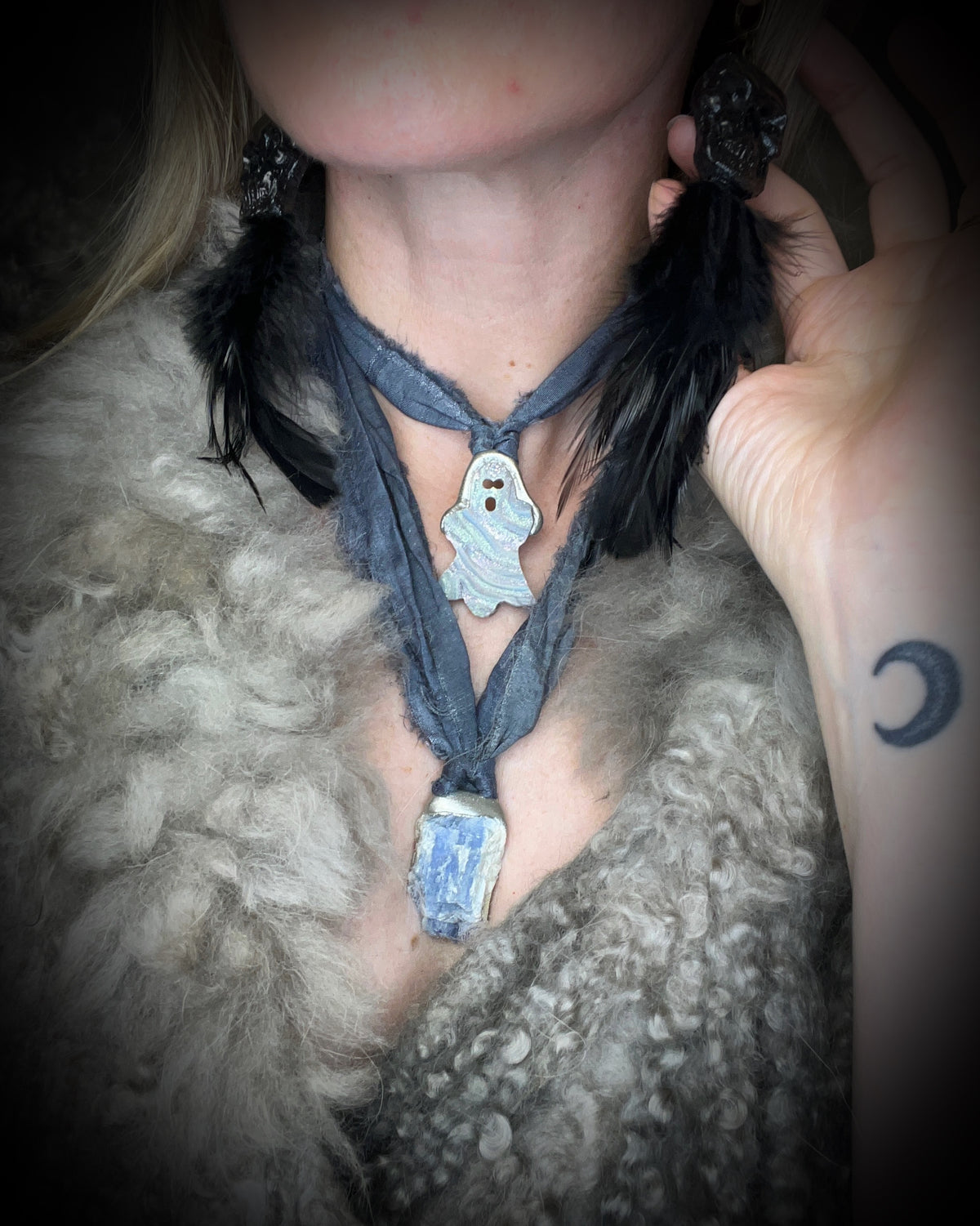 Small aura chalcedony ghost crystal carving with an iridescent glow in a sculptural silver-finish setting on dark gray recycled silk cords, handmade by Become Spellbound in Baltimore, Maryland.